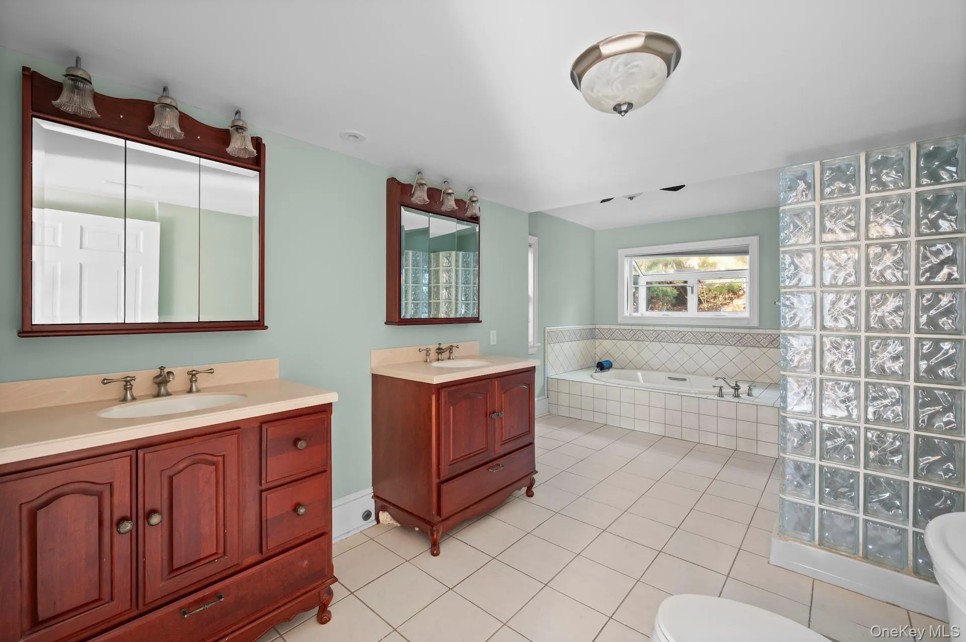 Full bathroom featuring a bath, two vanities, and light tile patterned flooring Full bathroom featuring a bath, two vanities, and light tile patterned flooring