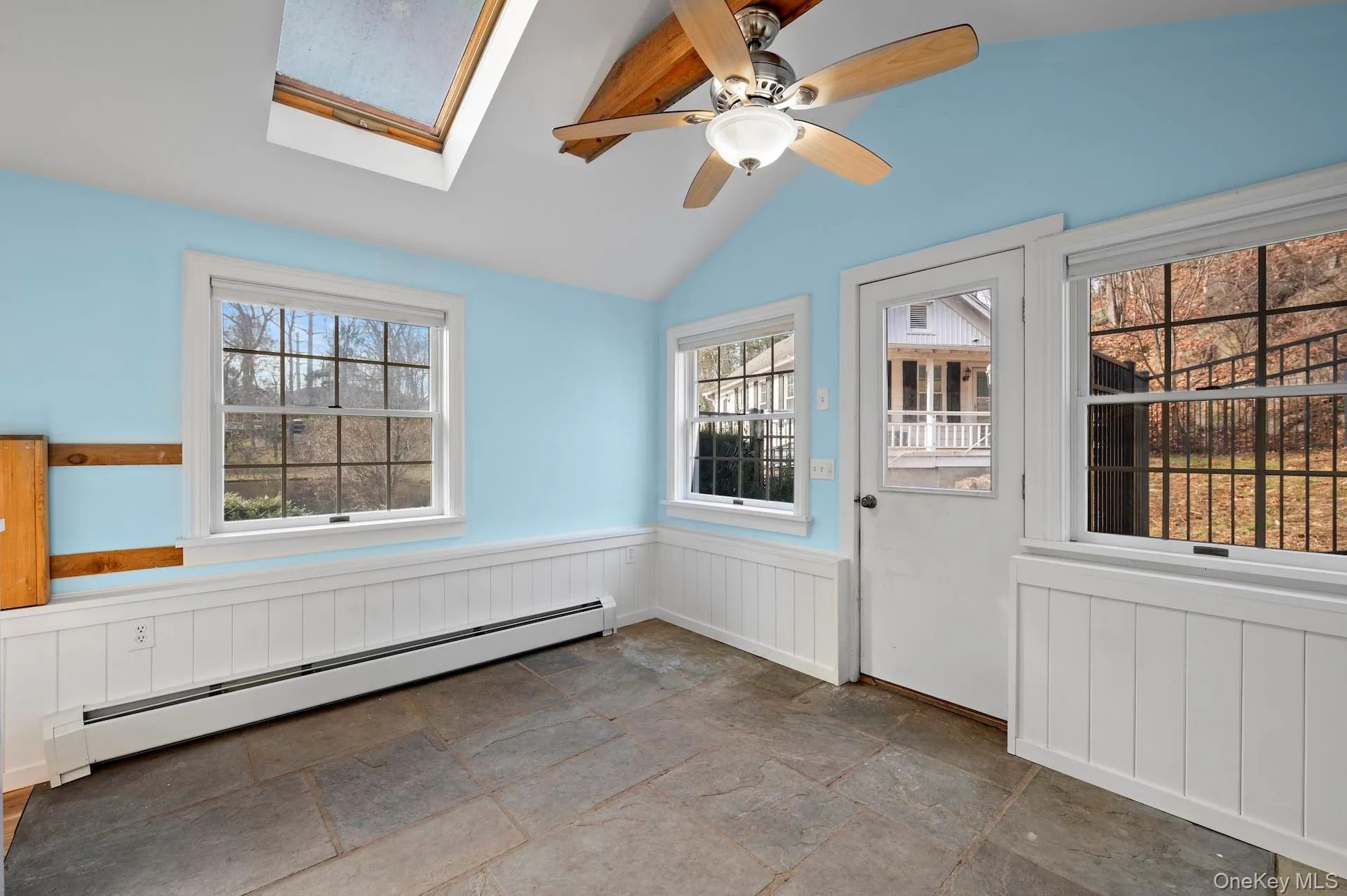 Unfurnished sunroom with a baseboard radiator, a skylight, and lofted ceiling Unfurnished sunroom with a baseboard radiator, a skylight, and lofted ceiling