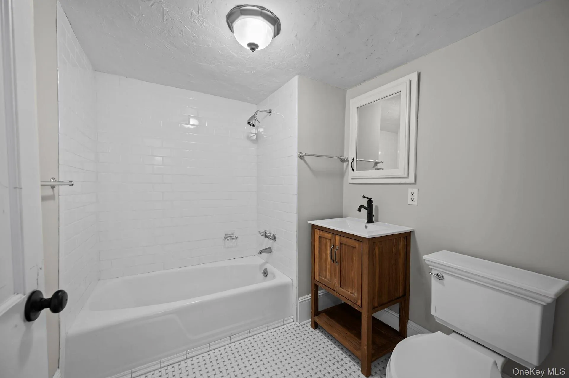 Full bath featuring shower combination, vanity, and a textured ceiling Full bath featuring shower combination, vanity, and a textured ceiling