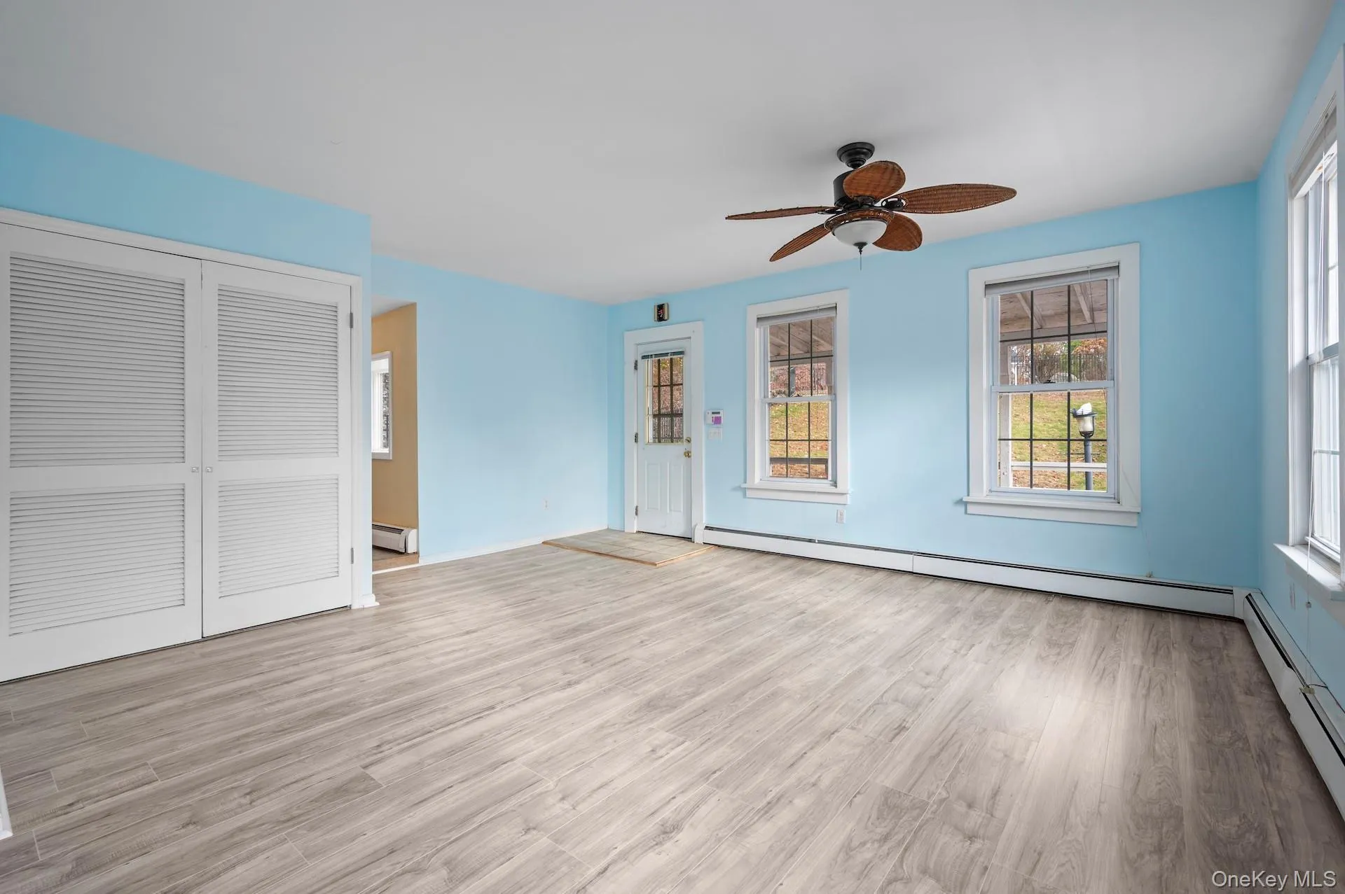 Unfurnished living room with a baseboard heating unit, light wood-style flooring, and ceiling fan Unfurnished living room with a baseboard heating unit, light wood-style flooring, and ceiling fan