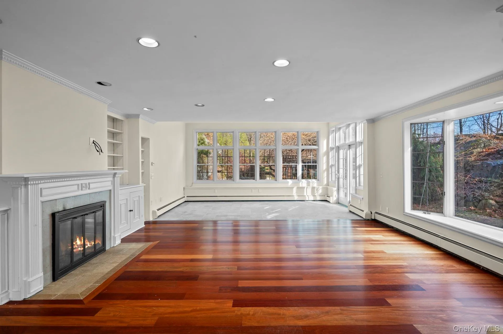 Unfurnished living room featuring a fireplace, built in shelves, crown molding, recessed lighting, and dark wood-type flooring Unfurnished living room featuring a fireplace, built in shelves, crown molding, recessed lighting, and dark wood-type flooring