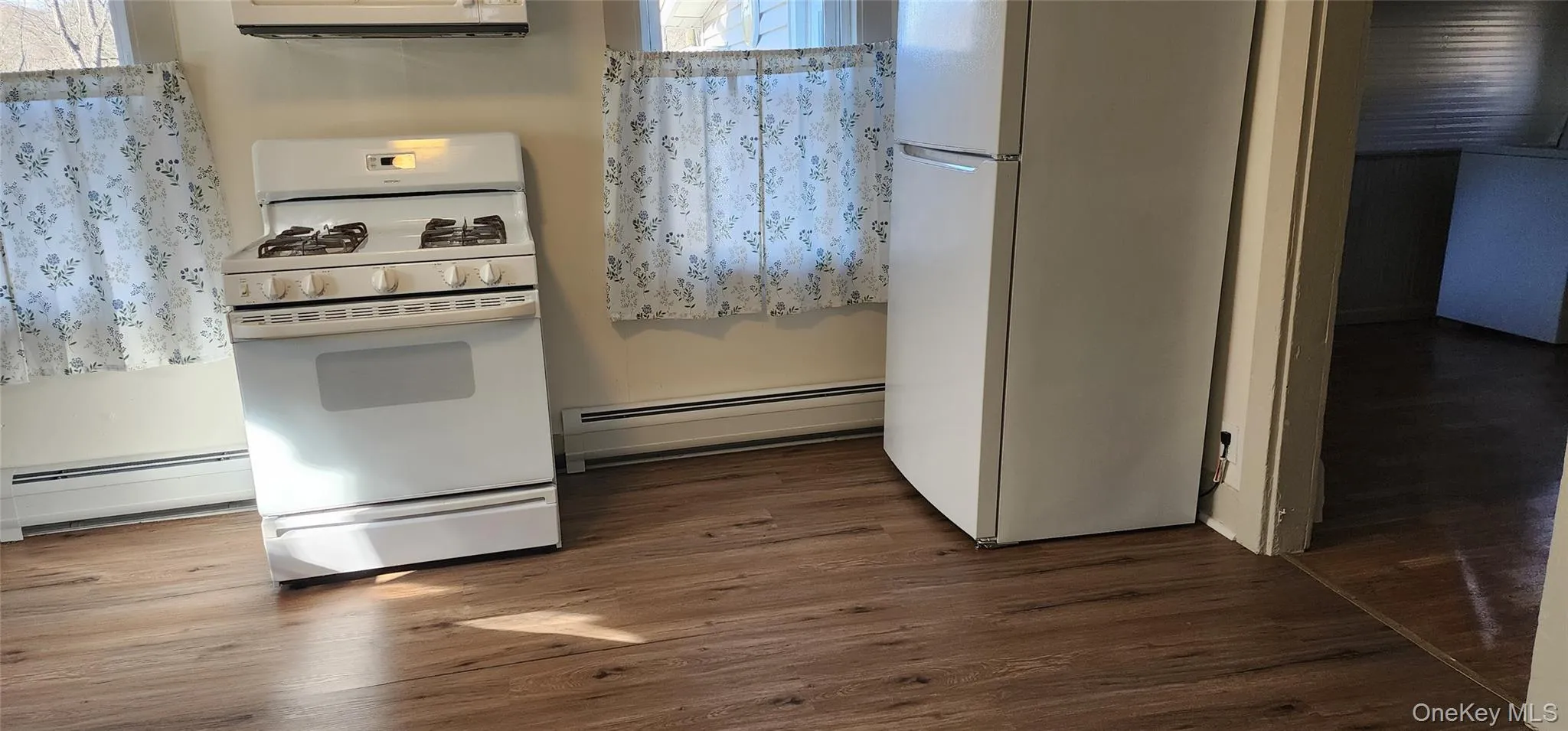 Kitchen featuring white appliances, a baseboard radiator, dark wood-style flooring, and extractor fan Kitchen featuring white appliances, a baseboard radiator, dark wood-style flooring, and extractor fan