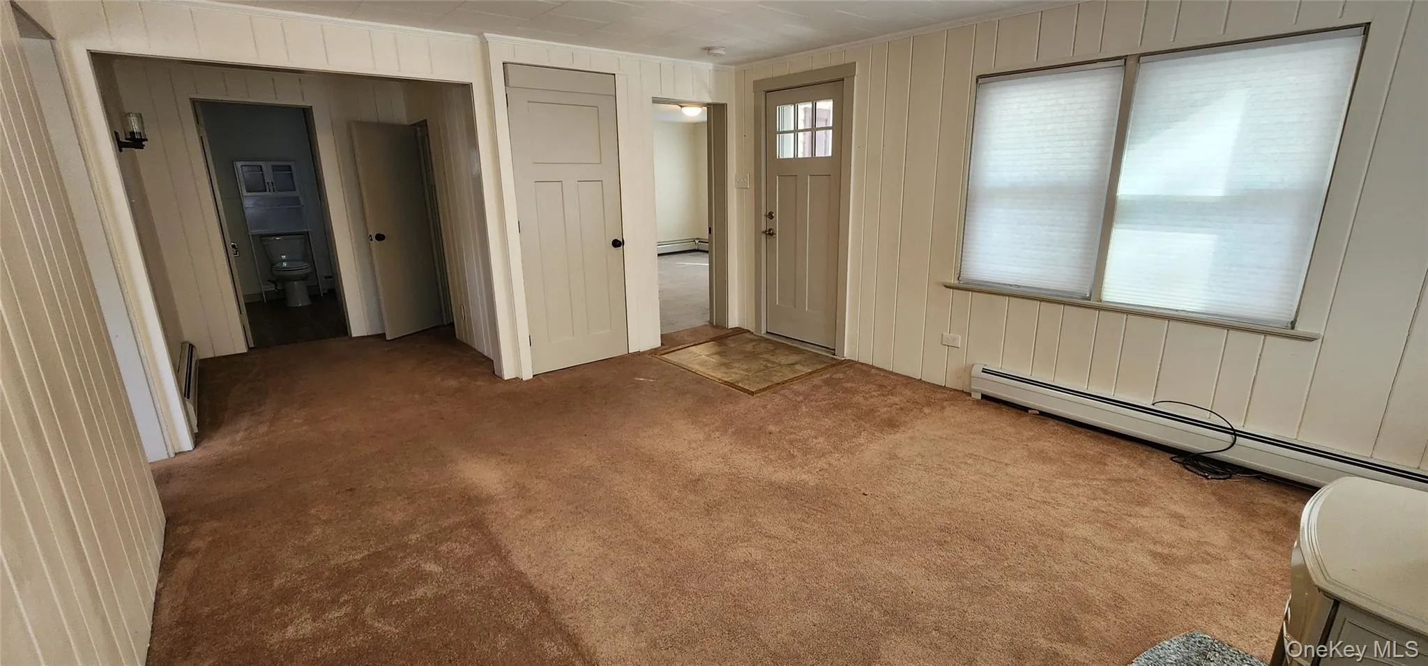 Entryway with wood walls, baseboard heating, and carpet Entryway with wood walls, baseboard heating, and carpet