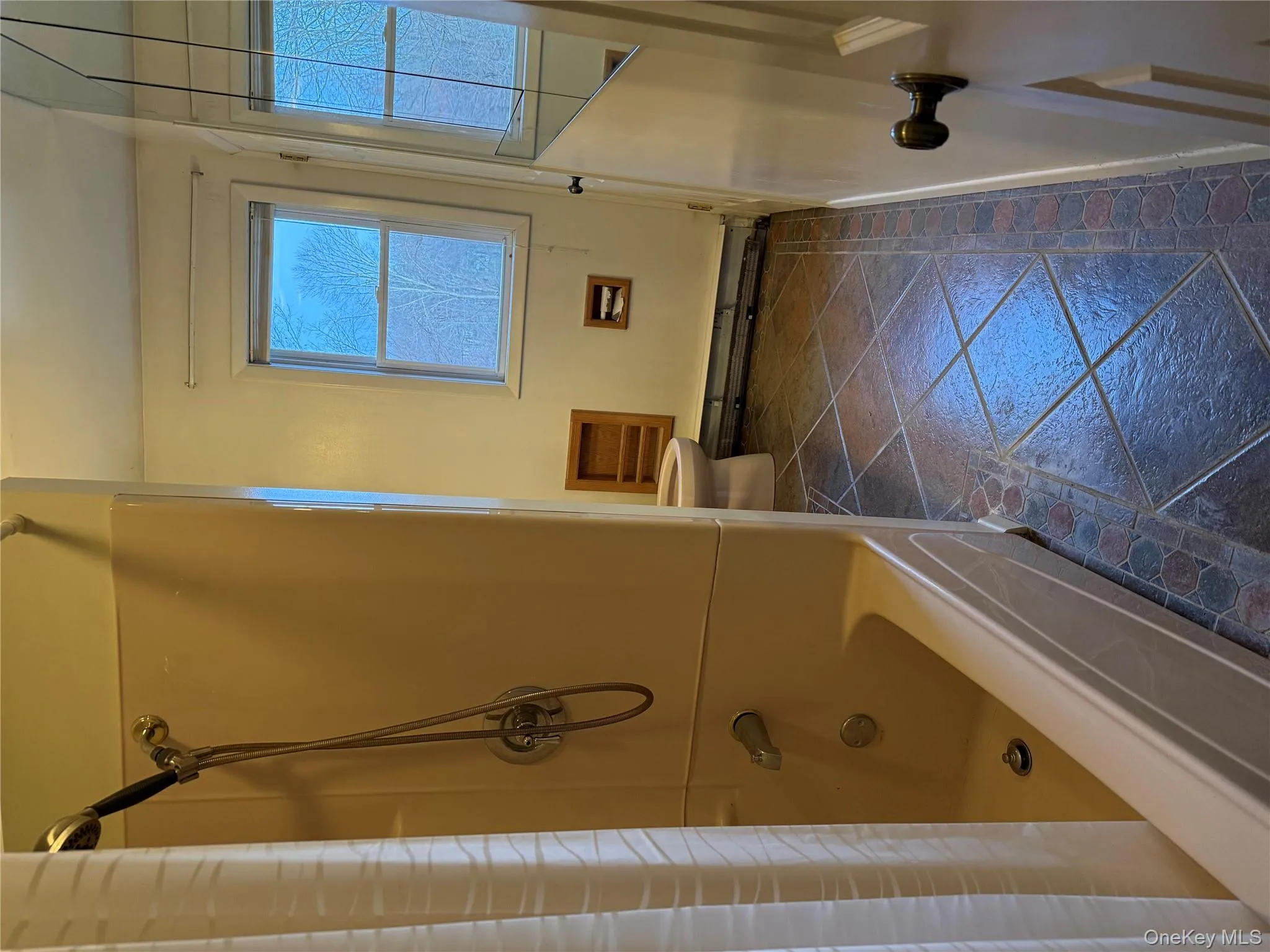 Bathroom with shower / bath combo, a baseboard heating unit, and stone tile floors Bathroom with shower / bath combo, a baseboard heating unit, and stone tile floors