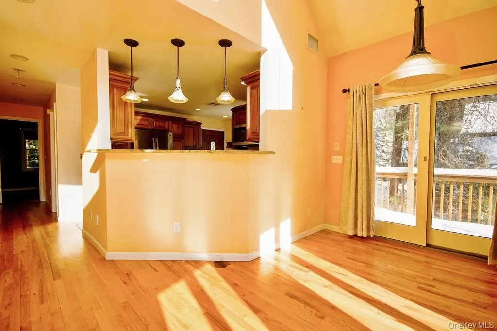 Kitchen featuring hanging light fixtures, stainless steel refrigerator, light wood finished floors, and brown cabinetry Kitchen featuring hanging light fixtures, stainless steel refrigerator, light wood finished floors, and brown cabinetry