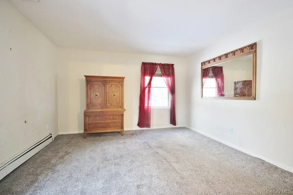 Carpeted empty room featuring a baseboard radiator and baseboards Carpeted empty room featuring a baseboard radiator and baseboards