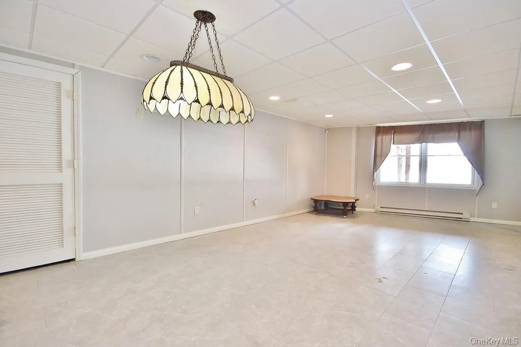 Empty room with a paneled ceiling, baseboard heating, light floors, and recessed lighting Empty room with a paneled ceiling, baseboard heating, light floors, and recessed lighting