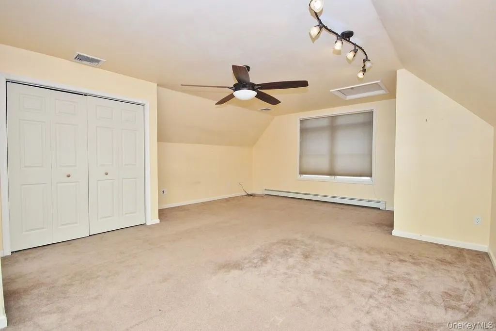 Bonus room with lofted ceiling, attic access, light colored carpet, a baseboard heating unit, and a ceiling fan Bonus room with lofted ceiling, attic access, light colored carpet, a baseboard heating unit, and a ceiling fan