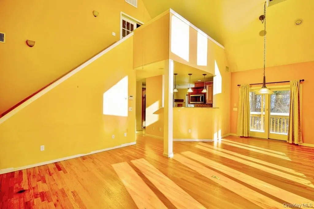 Unfurnished living room featuring high vaulted ceiling and light wood-type flooring Unfurnished living room featuring high vaulted ceiling and light wood-type flooring