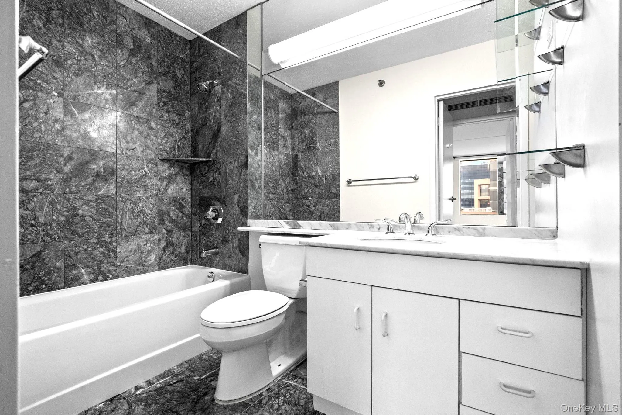 Bathroom featuring shower / bathtub combination, vanity, and marble look tile flooring Bathroom featuring shower / bathtub combination, vanity, and marble look tile flooring