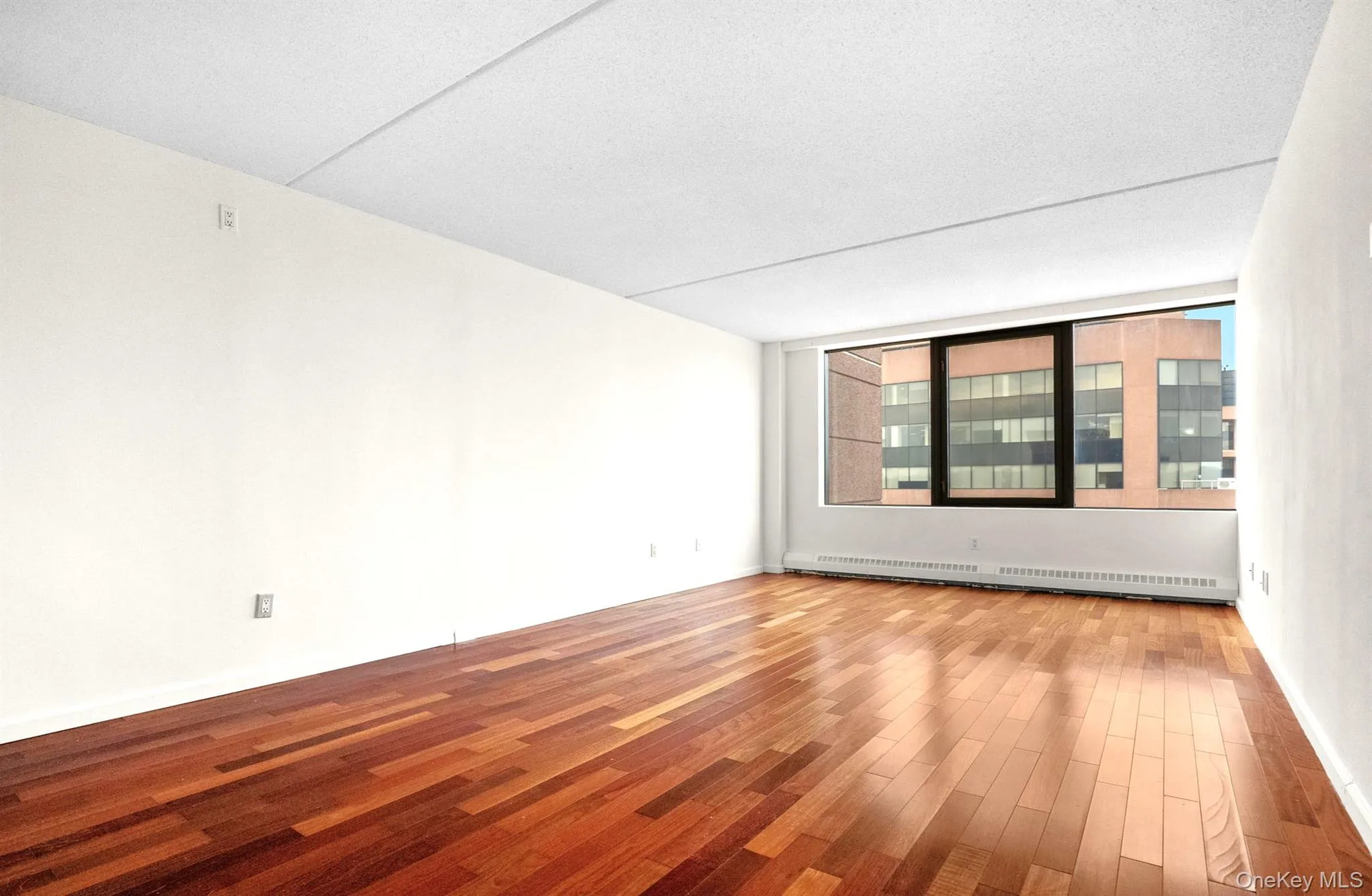 Unfurnished room featuring wood finished floors and baseboard heating Unfurnished room featuring wood finished floors and baseboard heating