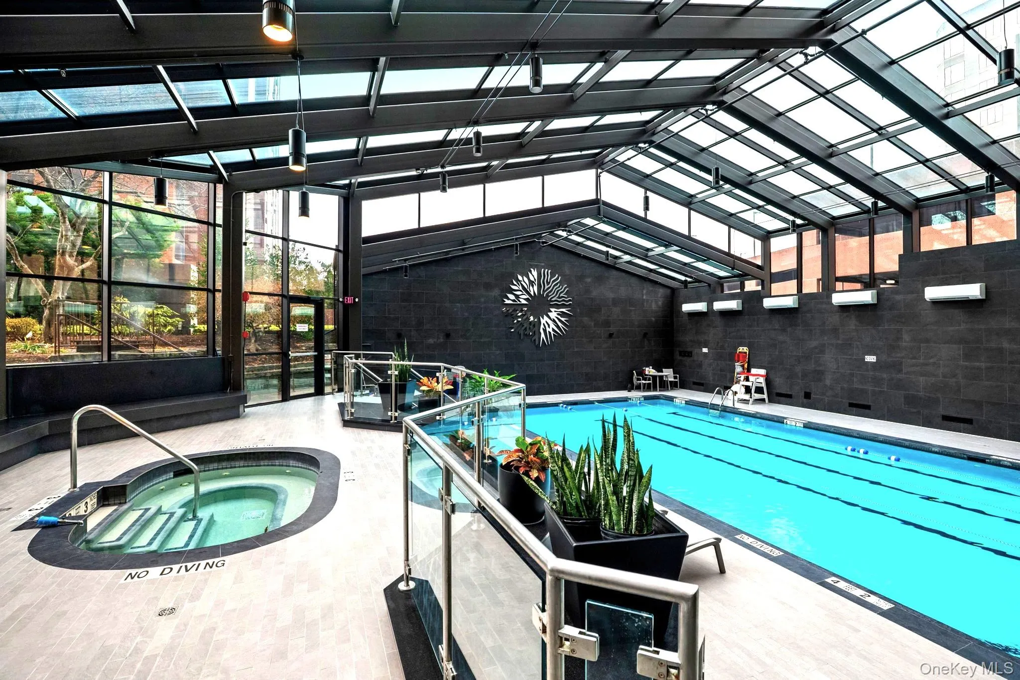 Indoor community pool featuring a lanai, a patio area, and a hot tub Indoor community pool featuring a lanai, a patio area, and a hot tub