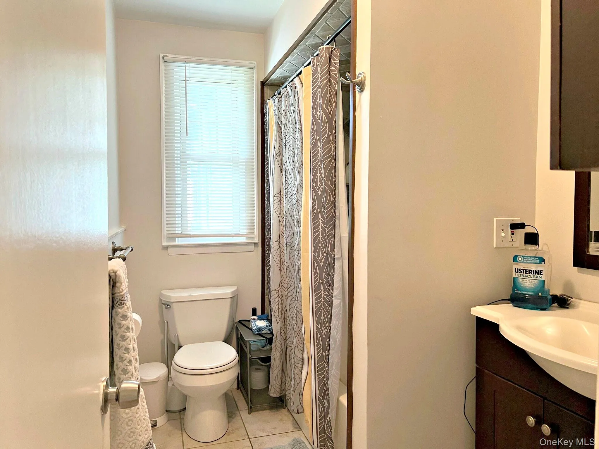 Bathroom featuring a shower with shower curtain, vanity, and light tile patterned floors Bathroom featuring a shower with shower curtain, vanity, and light tile patterned floors