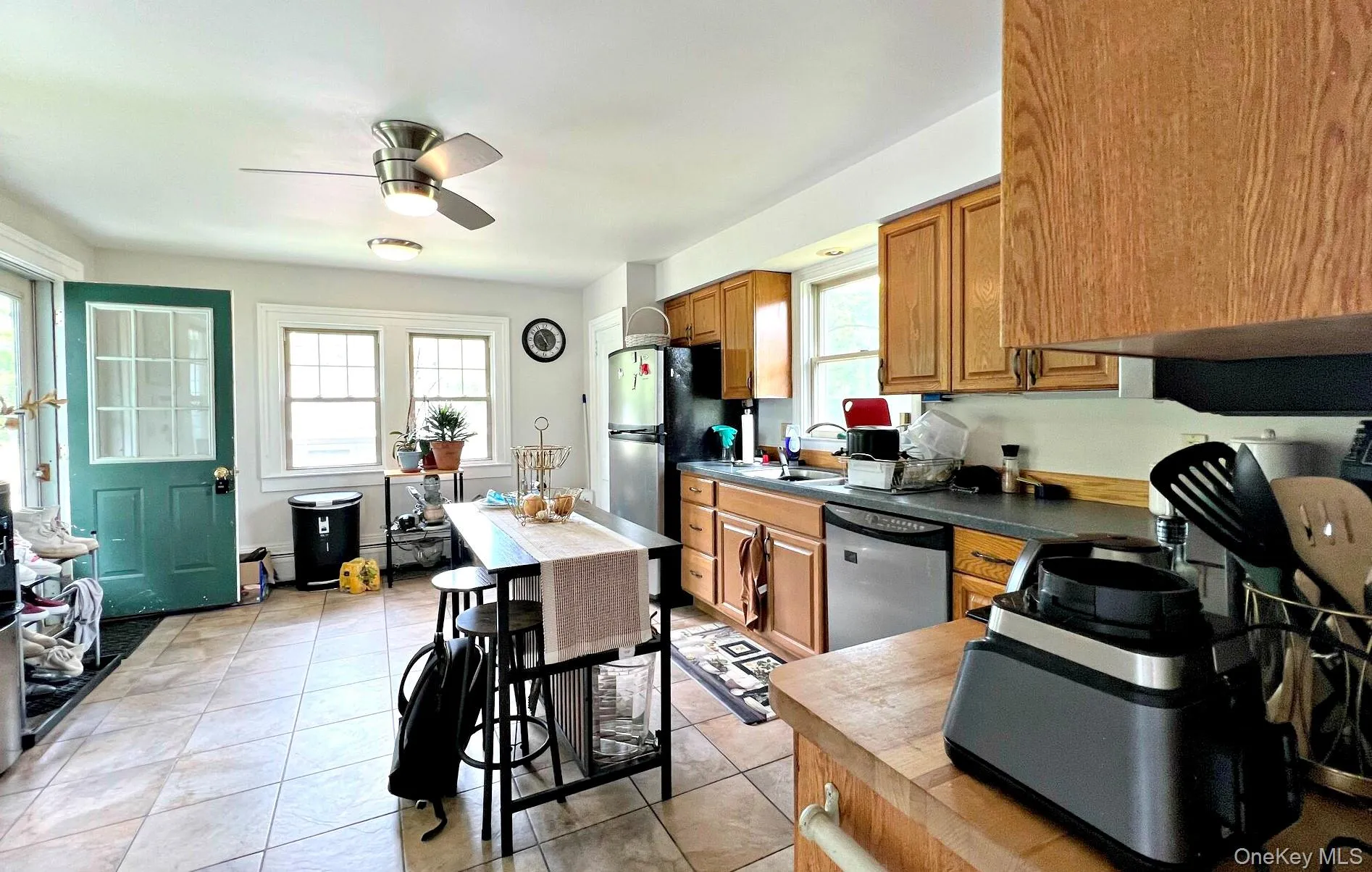 Kitchen featuring appliances with stainless steel finishes, brown cabinetry, a ceiling fan, and light tile patterned flooring Kitchen featuring appliances with stainless steel finishes, brown cabinetry, a ceiling fan, and light tile patterned flooring