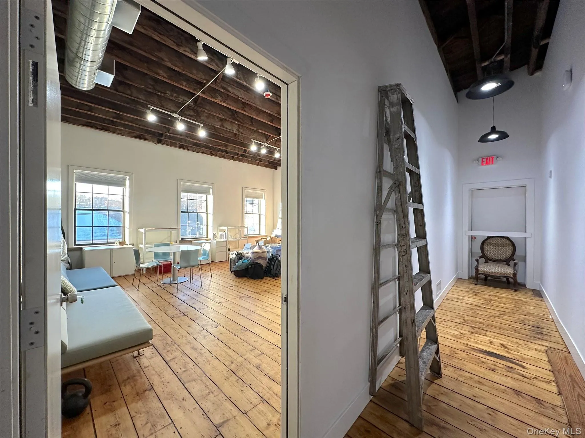 Hallway with light wood-style flooring, a wood ceiling with exposed beams, and track lighting Hallway with light wood-style flooring, a wood ceiling with exposed beams, and track lighting