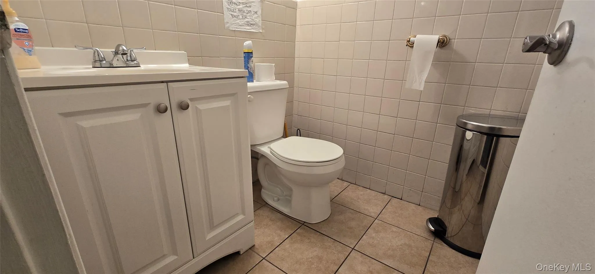 Bathroom featuring tile walls, vanity, and light tile patterned floors Bathroom featuring tile walls, vanity, and light tile patterned floors