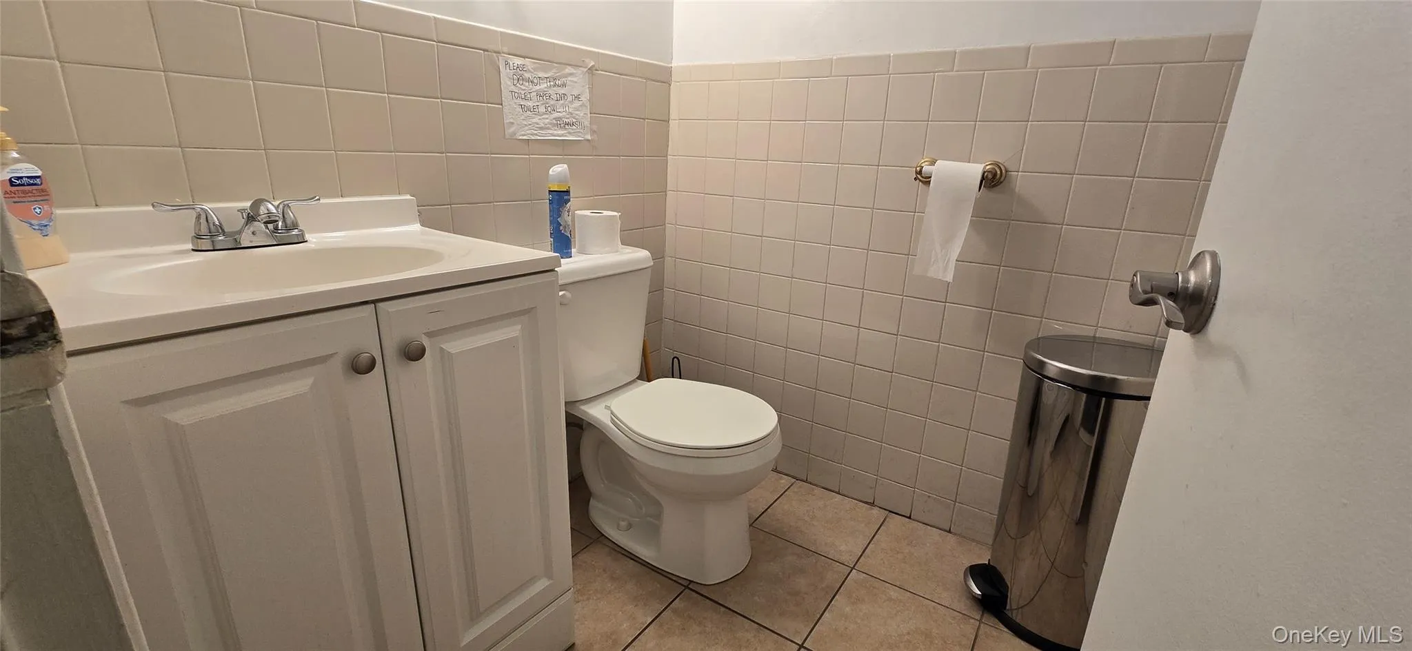 Half bathroom featuring tile walls, vanity, and light tile patterned flooring Half bathroom featuring tile walls, vanity, and light tile patterned flooring
