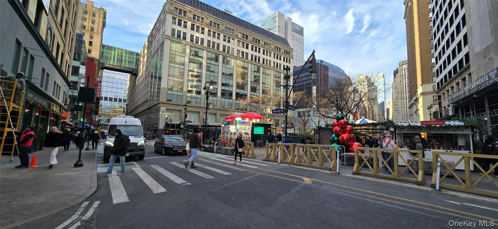 View of asphalt road featuring a city view, sidewalks, street lights, and curbs View of asphalt road featuring a city view, sidewalks, street lights, and curbs