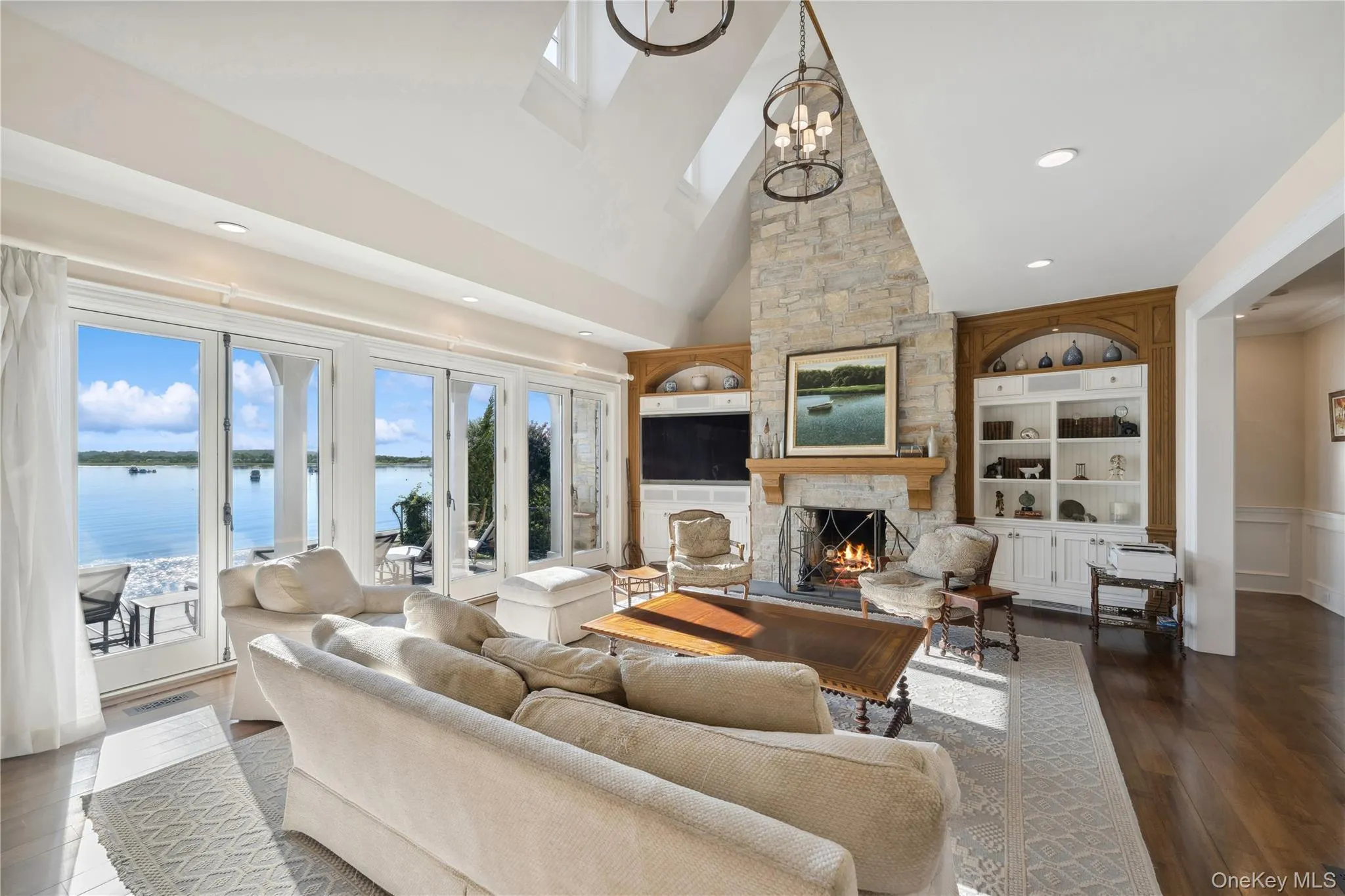 Living area with built in shelves, a stone fireplace, high vaulted ceiling, dark wood-type flooring, and recessed lighting Living area with built in shelves, a stone fireplace, high vaulted ceiling, dark wood-type flooring, and recessed lighting