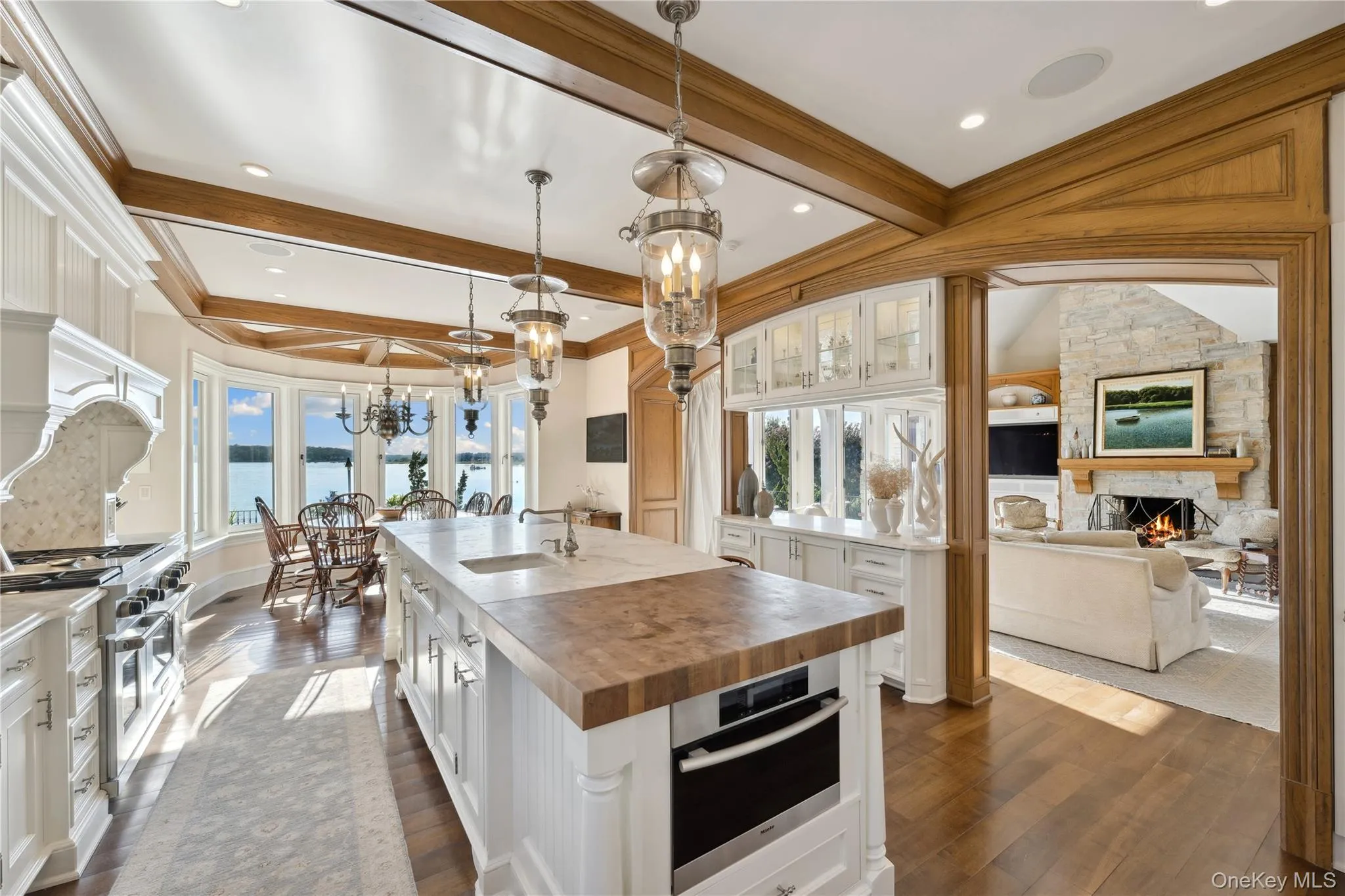 Kitchen featuring butcher block counters, decorative light fixtures, a kitchen island with sink, white cabinetry, and appliances with stainless steel finishes Kitchen featuring butcher block counters, decorative light fixtures, a kitchen island with sink, white cabinetry, and appliances with stainless steel finishes