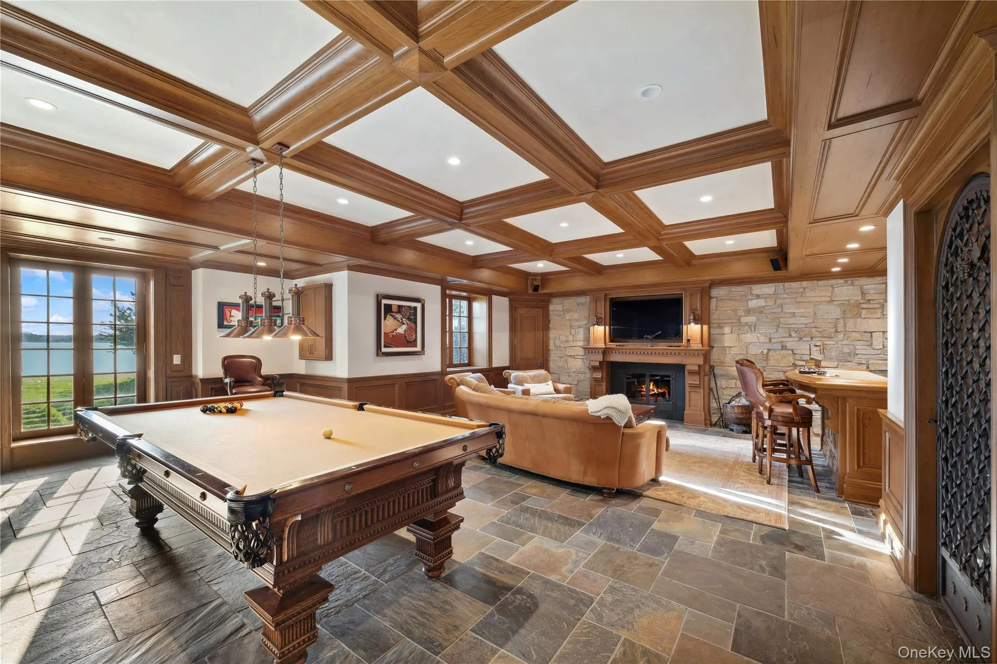 Game room featuring billiards, a glass covered fireplace, wainscoting, french doors, and coffered ceiling Game room featuring billiards, a glass covered fireplace, wainscoting, french doors, and coffered ceiling