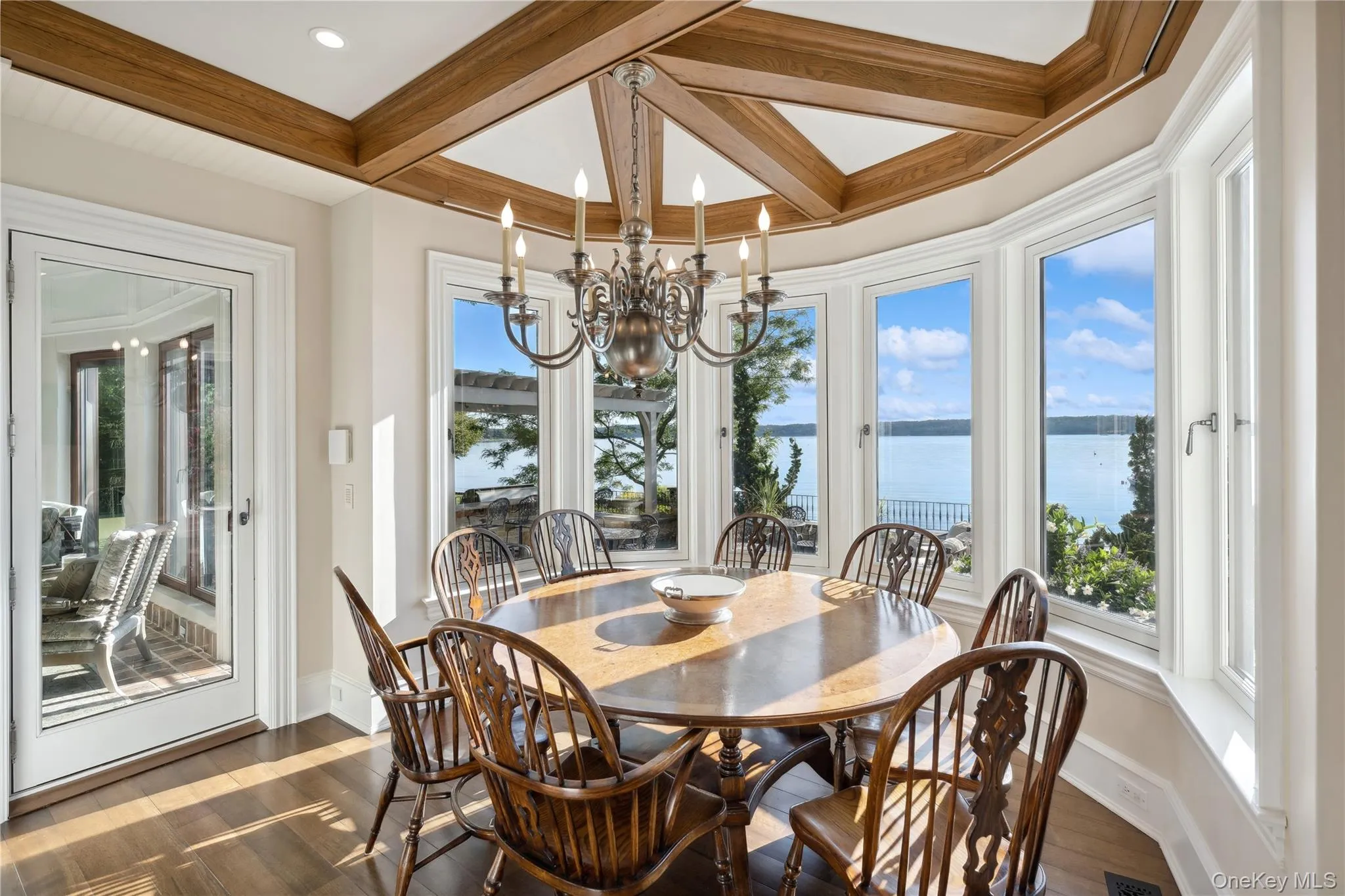 Dining space with a water view, beamed ceiling, dark wood finished floors, coffered ceiling, and a chandelier Dining space with a water view, beamed ceiling, dark wood finished floors, coffered ceiling, and a chandelier