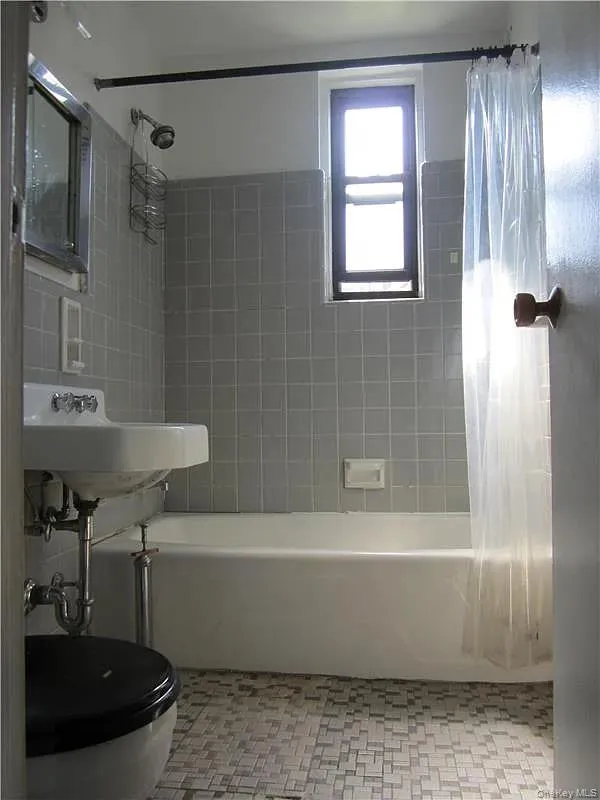 Bathroom featuring shower / bath combination with curtain and a sink Bathroom featuring shower / bath combination with curtain and a sink