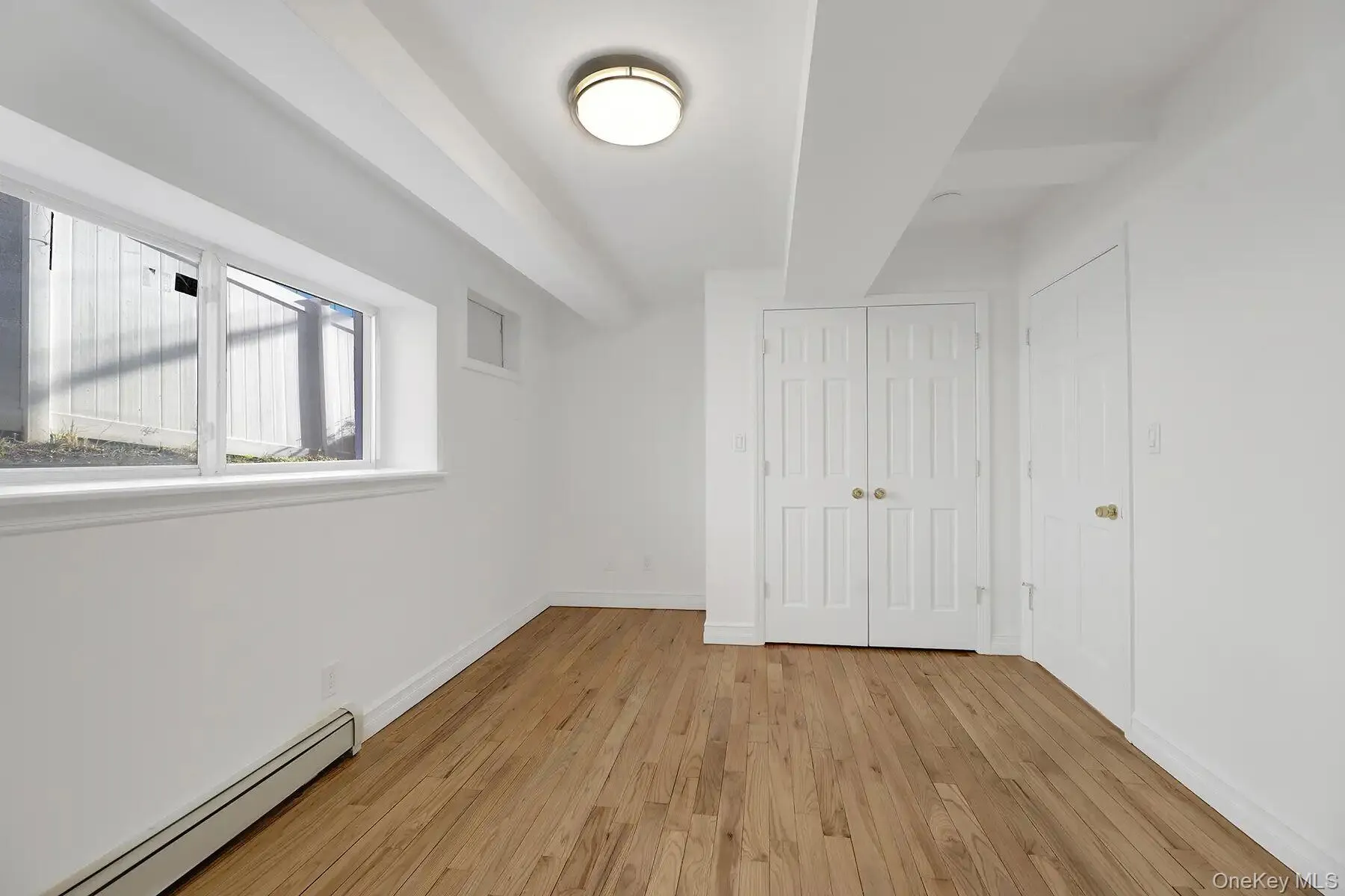 Unfurnished bedroom with a baseboard heating unit, light wood-type flooring, and a closet Unfurnished bedroom with a baseboard heating unit, light wood-type flooring, and a closet