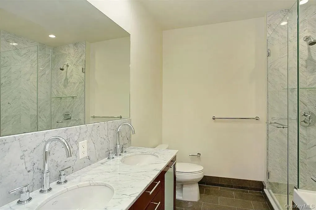 Bathroom featuring double vanity, a marble finish shower, dark tile patterned floors, recessed lighting, and backsplash Bathroom featuring double vanity, a marble finish shower, dark tile patterned floors, recessed lighting, and backsplash