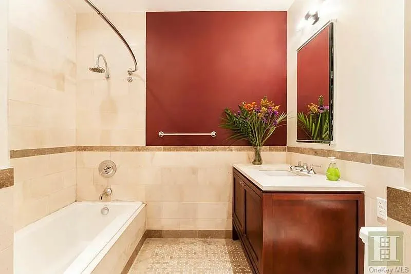 Bathroom featuring shower / bath combination, vanity, tile walls, and wainscoting Bathroom featuring shower / bath combination, vanity, tile walls, and wainscoting