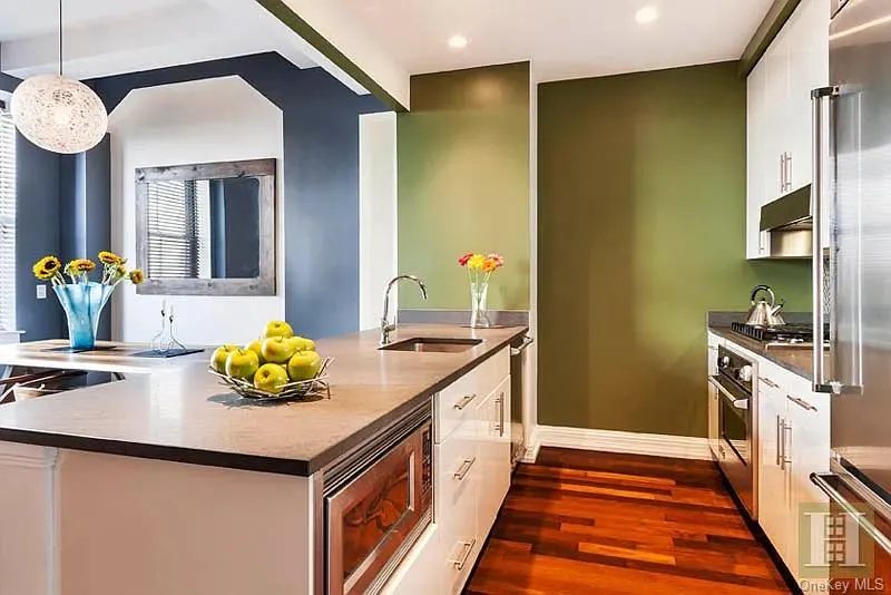 Kitchen with white cabinetry, stainless steel appliances, dark wood-style flooring, under cabinet range hood, and dark stone countertops Kitchen with white cabinetry, stainless steel appliances, dark wood-style flooring, under cabinet range hood, and dark stone countertops