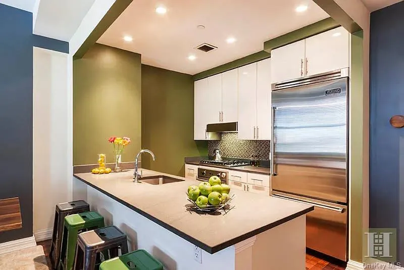 Kitchen with a kitchen breakfast bar, white cabinetry, appliances with stainless steel finishes, a peninsula, and recessed lighting Kitchen with a kitchen breakfast bar, white cabinetry, appliances with stainless steel finishes, a peninsula, and recessed lighting