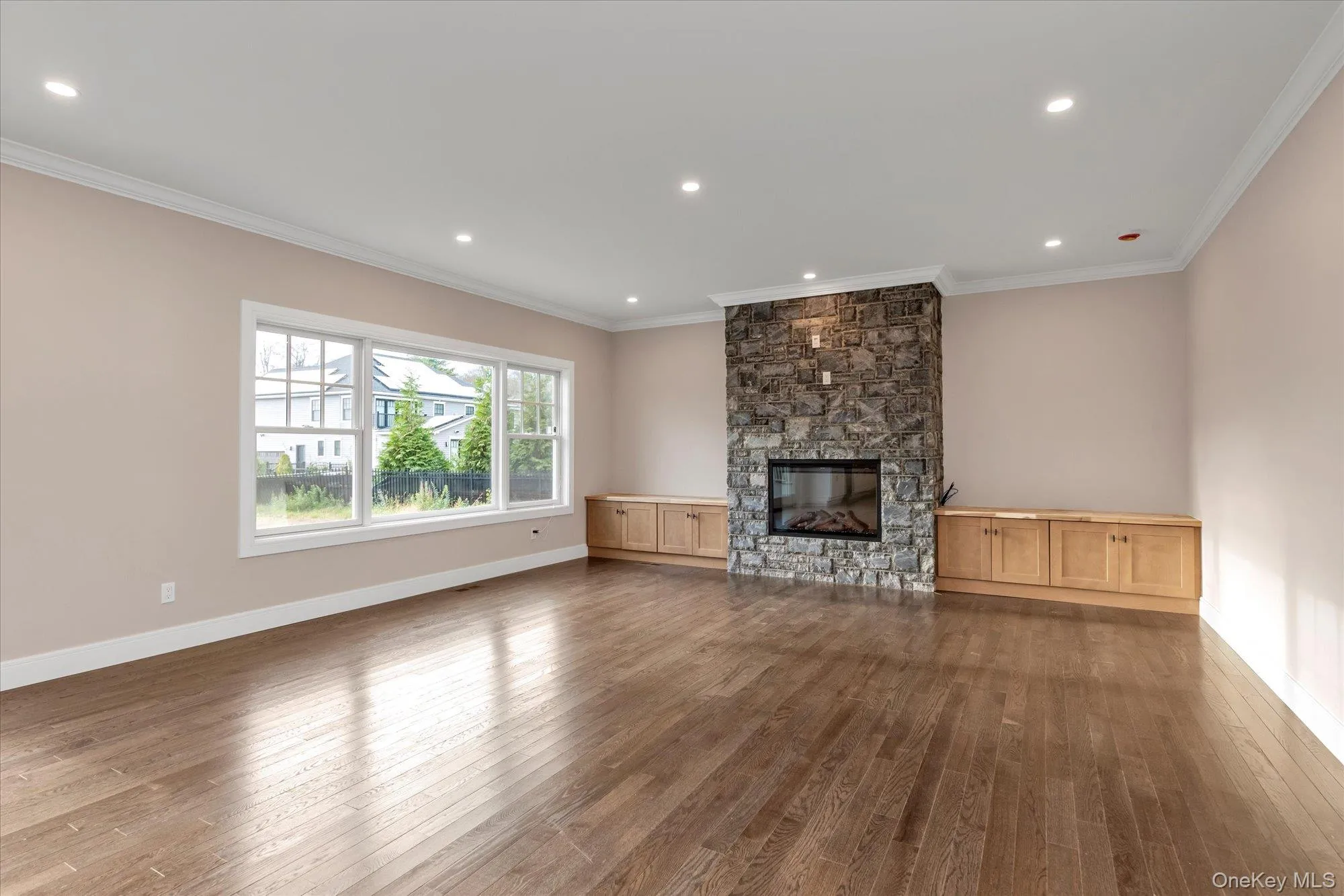 Unfurnished living room featuring ornamental molding, hardwood / wood-style flooring, a stone fireplace, and recessed lighting Unfurnished living room featuring ornamental molding, hardwood / wood-style flooring, a stone fireplace, and recessed lighting