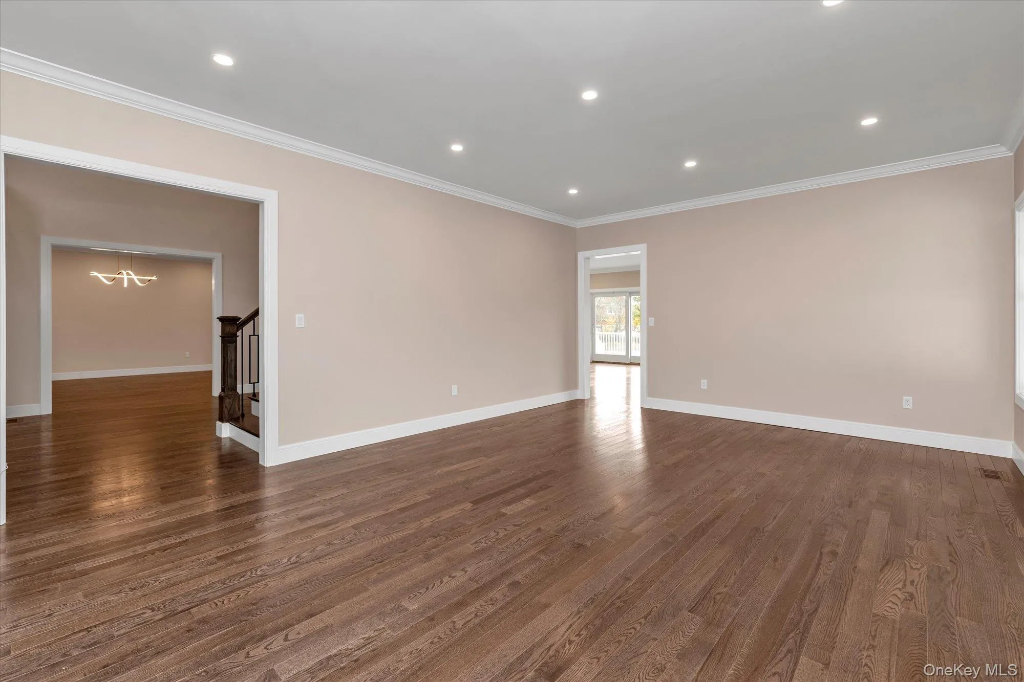 Spare room with a chandelier, recessed lighting, dark wood-style flooring, stairway, and crown molding Spare room with a chandelier, recessed lighting, dark wood-style flooring, stairway, and crown molding