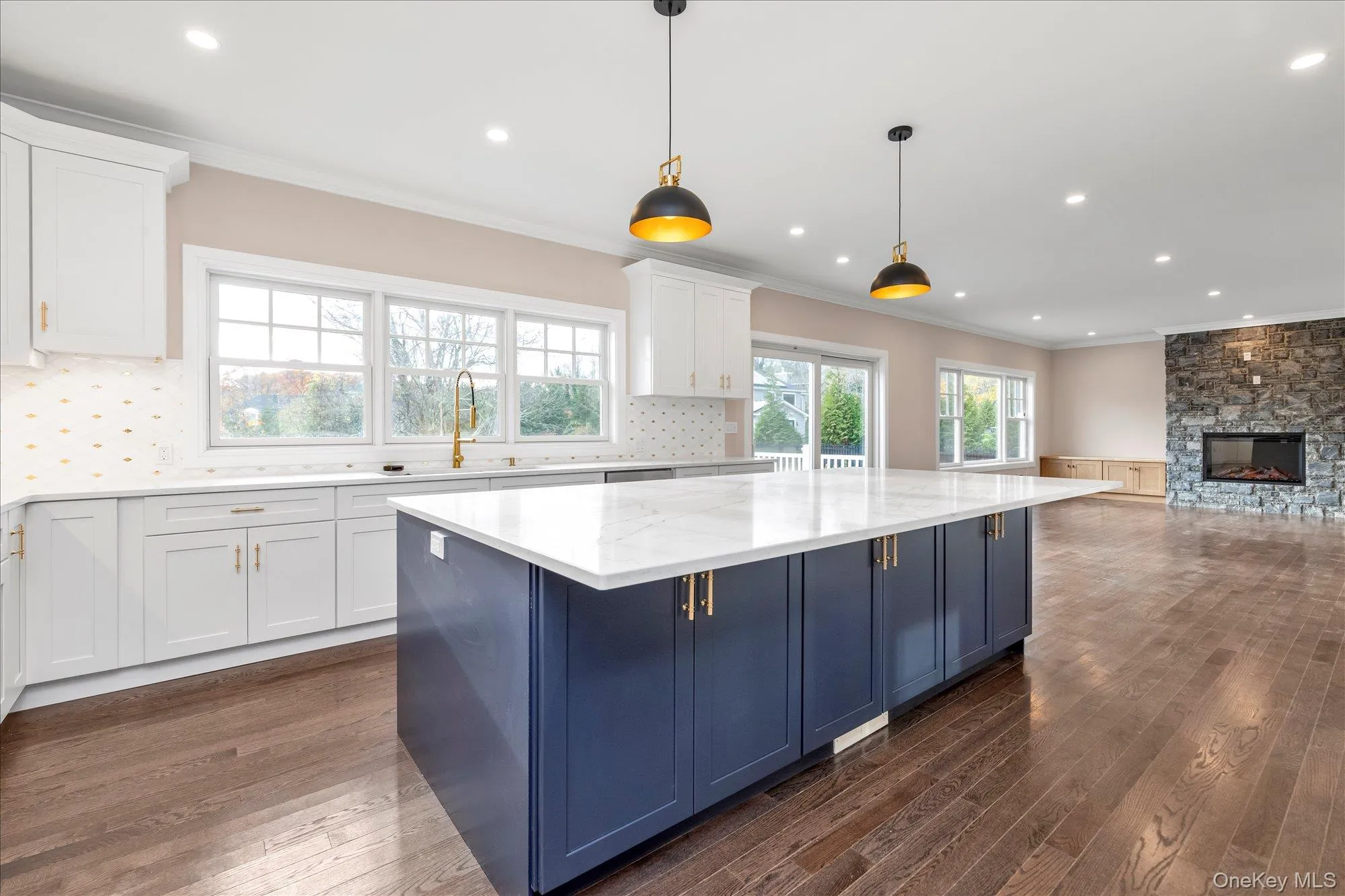 Kitchen with blue cabinetry, white cabinets, crown molding, open floor plan, and light stone countertops Kitchen with blue cabinetry, white cabinets, crown molding, open floor plan, and light stone countertops