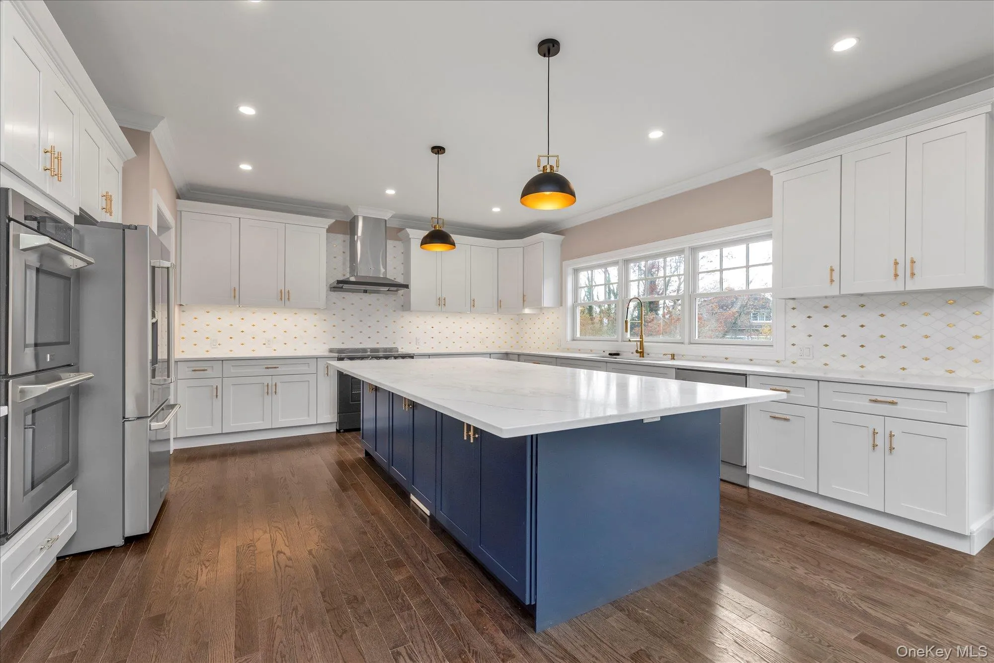 Kitchen with blue cabinetry, hanging light fixtures, ornamental molding, white cabinetry, and stainless steel appliances Kitchen with blue cabinetry, hanging light fixtures, ornamental molding, white cabinetry, and stainless steel appliances
