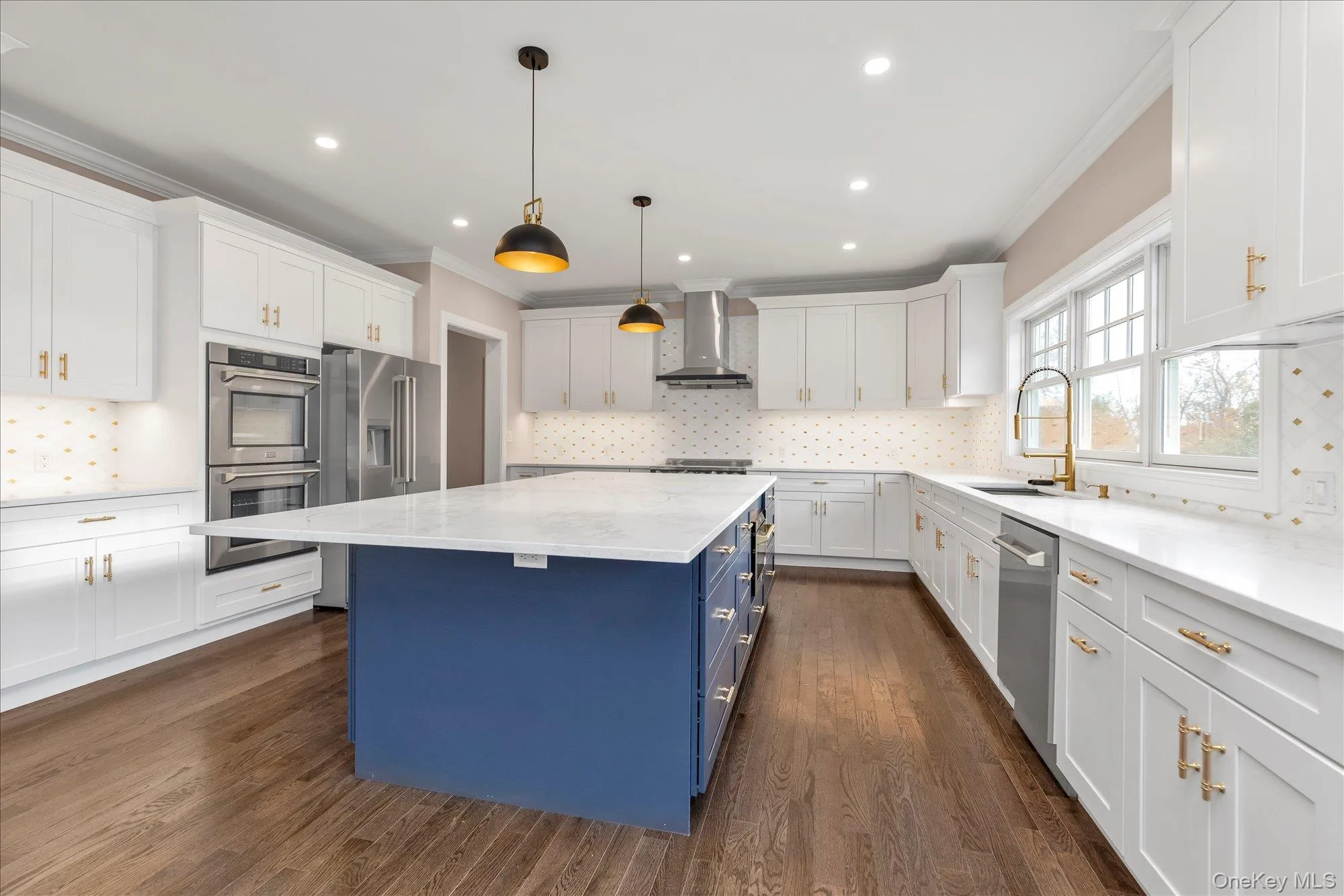 Kitchen with blue cabinets, crown molding, decorative backsplash, pendant lighting, and appliances with stainless steel finishes Kitchen with blue cabinets, crown molding, decorative backsplash, pendant lighting, and appliances with stainless steel finishes