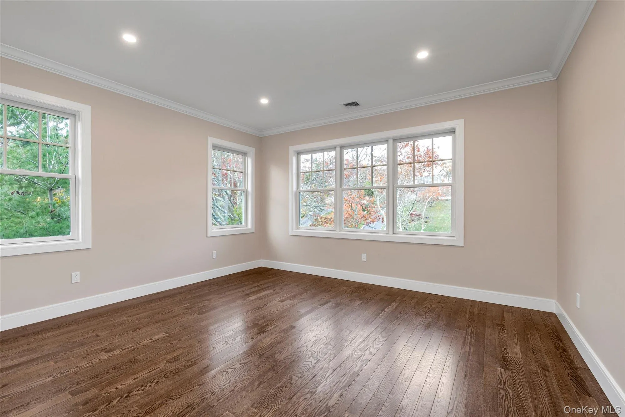 Empty room with dark wood-type flooring, ornamental molding, healthy amount of natural light, and recessed lighting Empty room with dark wood-type flooring, ornamental molding, healthy amount of natural light, and recessed lighting