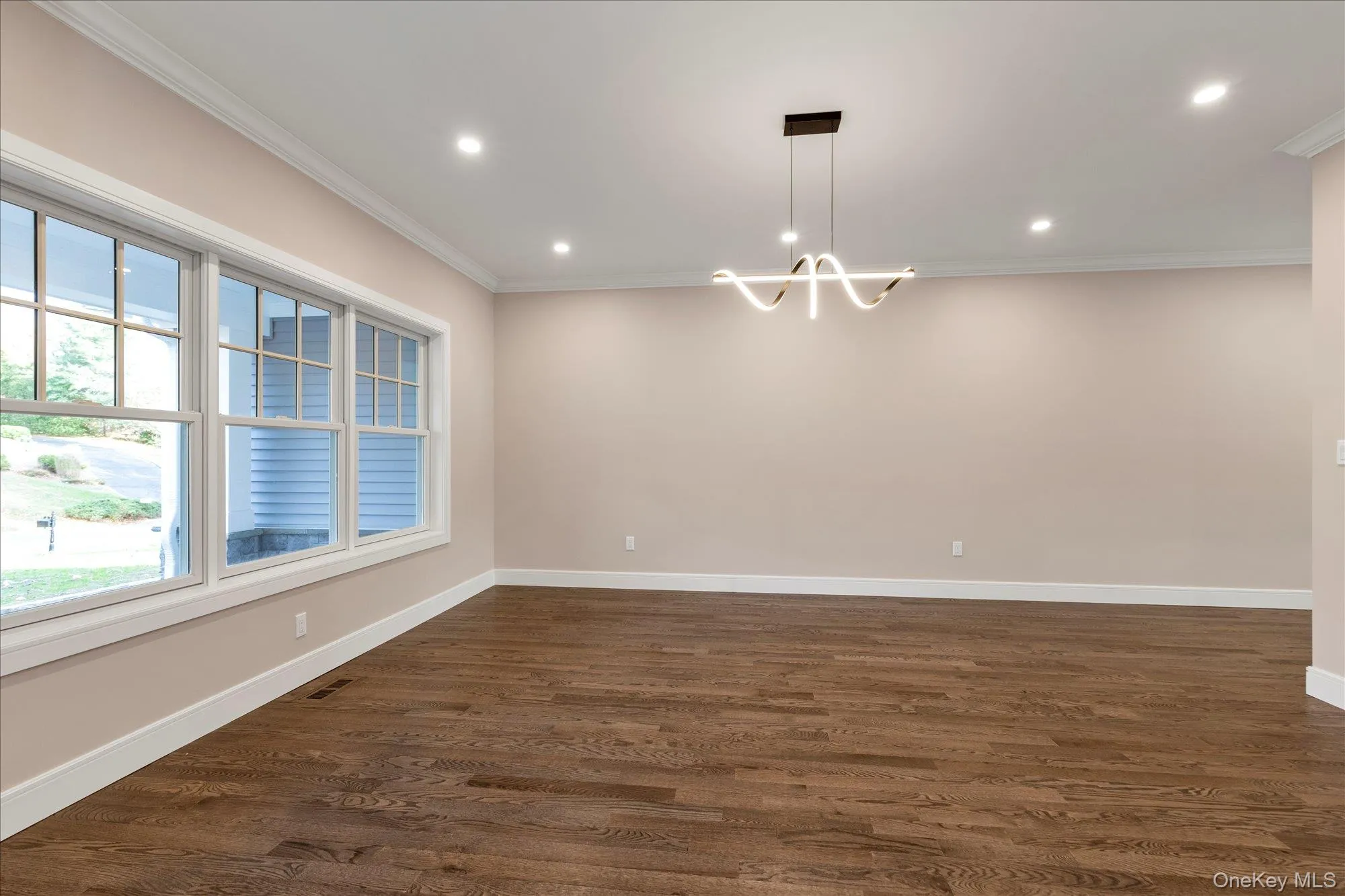 Unfurnished room with dark wood-type flooring, crown molding, recessed lighting, and a chandelier Unfurnished room with dark wood-type flooring, crown molding, recessed lighting, and a chandelier