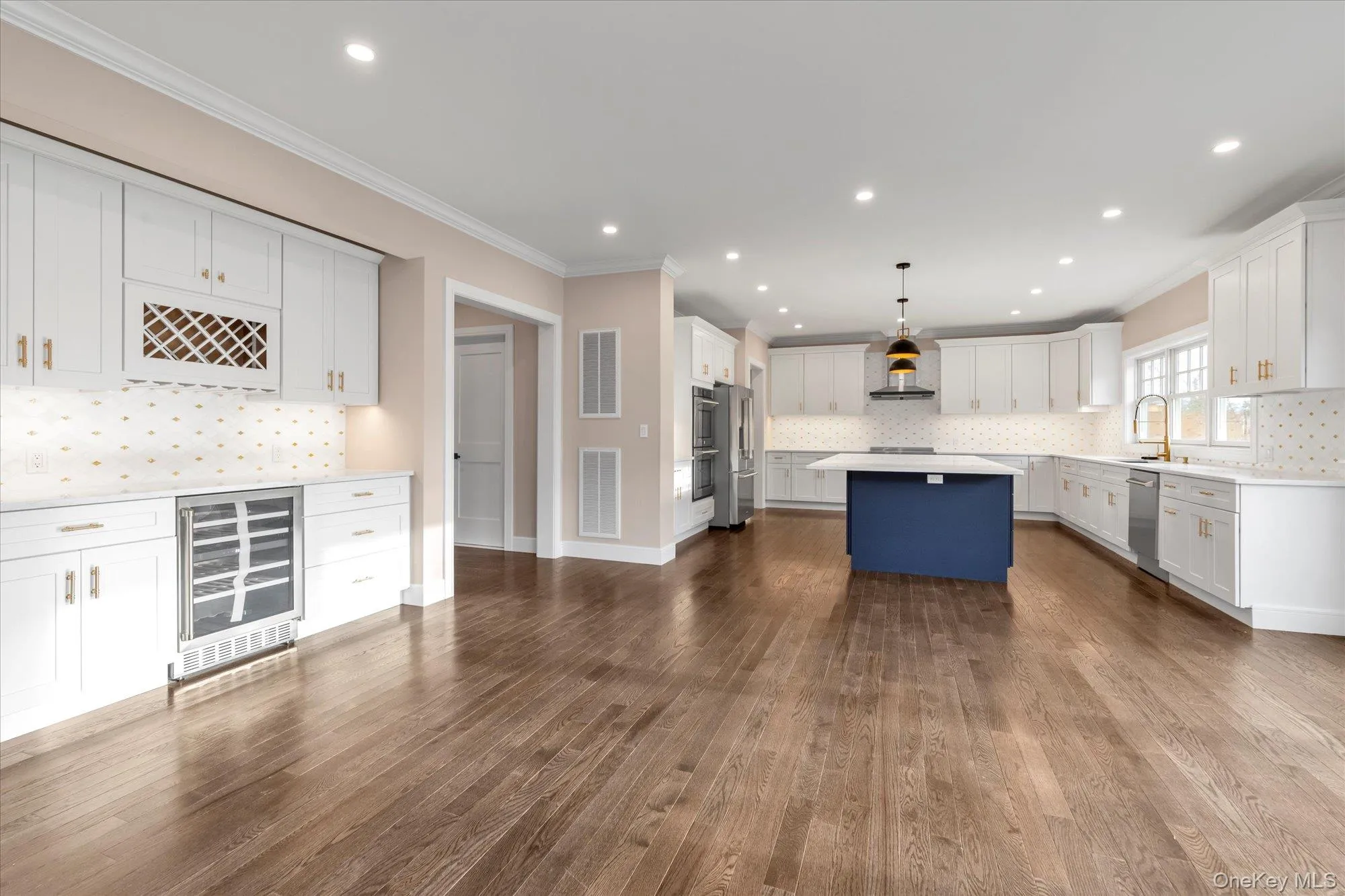 Kitchen featuring ornamental molding, white cabinetry, decorative light fixtures, decorative backsplash, and dark wood-style flooring Kitchen featuring ornamental molding, white cabinetry, decorative light fixtures, decorative backsplash, and dark wood-style flooring