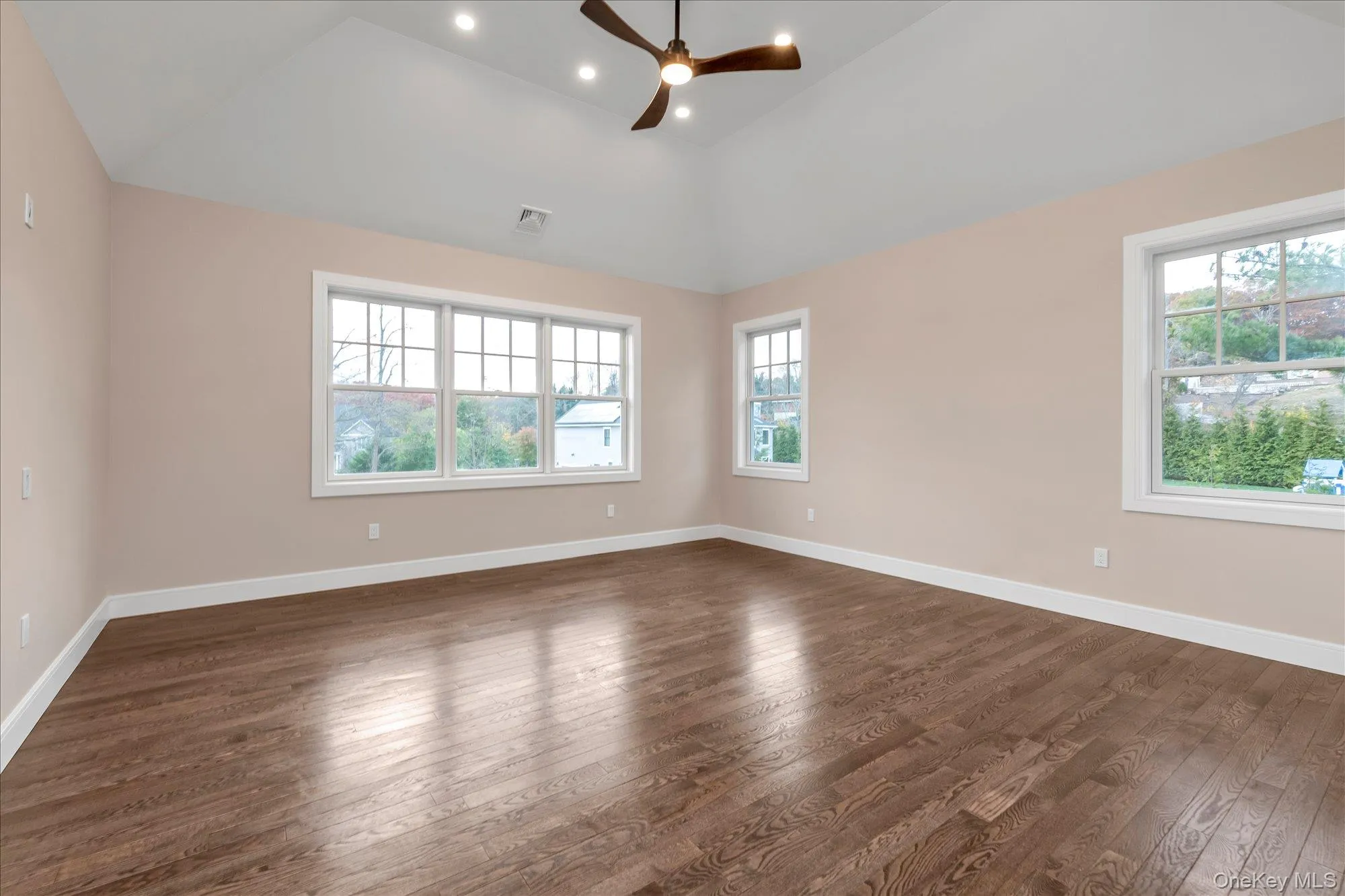 Spare room with dark wood-style floors, healthy amount of natural light, vaulted ceiling, ceiling fan, and recessed lighting Spare room with dark wood-style floors, healthy amount of natural light, vaulted ceiling, ceiling fan, and recessed lighting