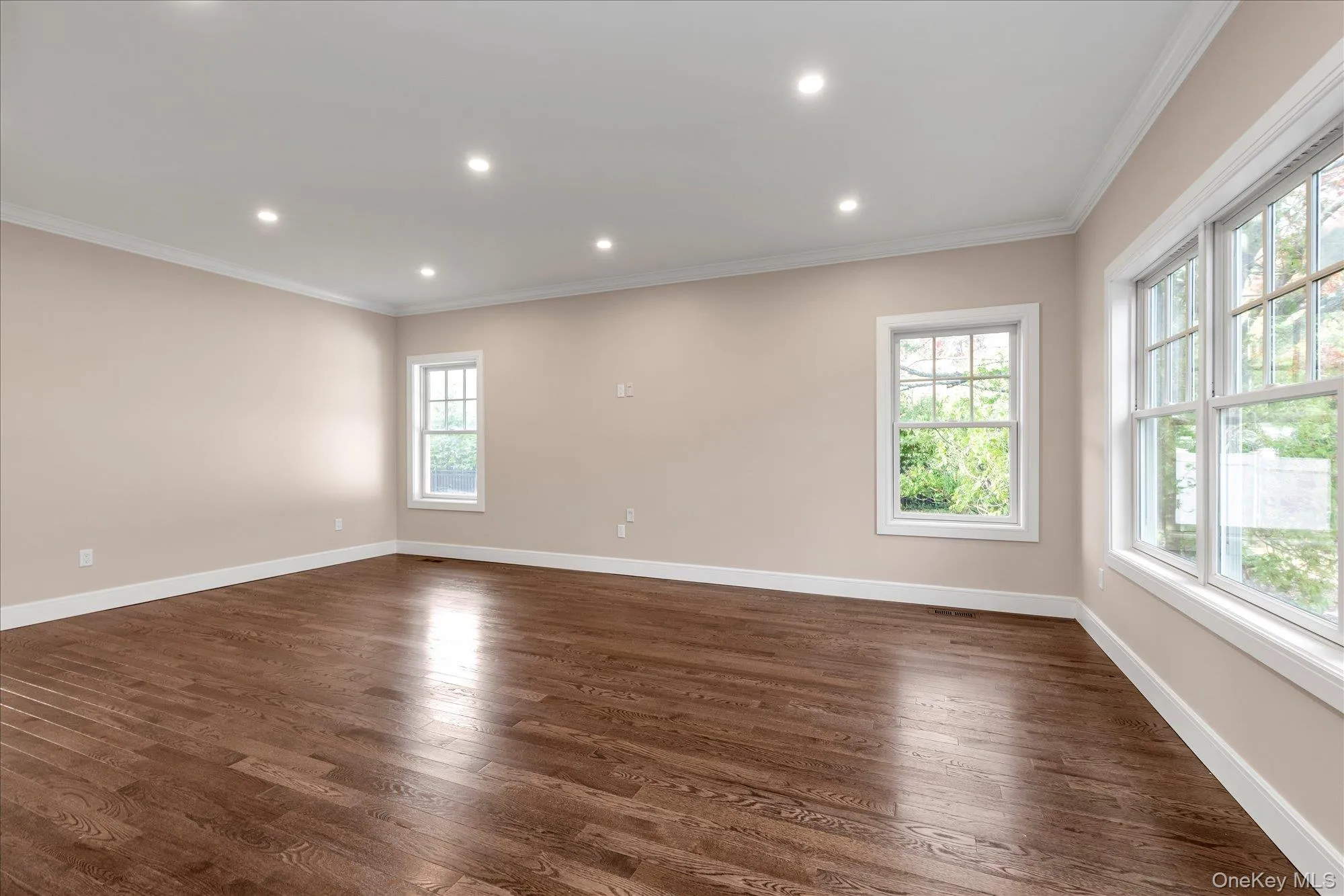 Empty room featuring dark wood finished floors, recessed lighting, and ornamental molding Empty room featuring dark wood finished floors, recessed lighting, and ornamental molding