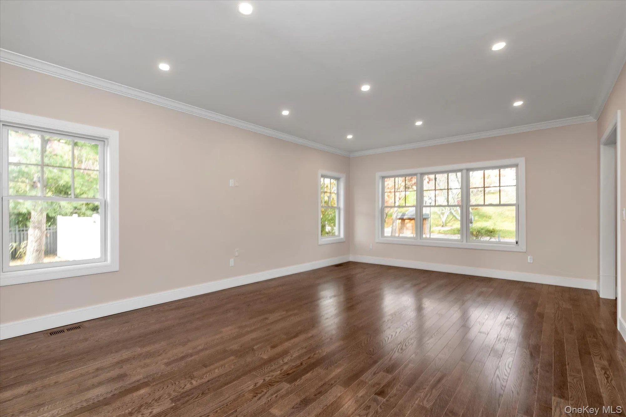 Spare room featuring dark wood-style flooring, crown molding, recessed lighting, and plenty of natural light Spare room featuring dark wood-style flooring, crown molding, recessed lighting, and plenty of natural light