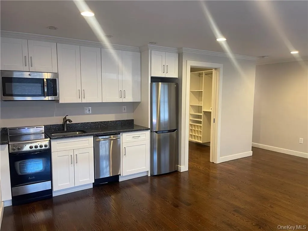 Kitchen featuring appliances with stainless steel finishes, white cabinetry, dark stone counters, recessed lighting, and ornamental molding Kitchen featuring appliances with stainless steel finishes, white cabinetry, dark stone counters, recessed lighting, and ornamental molding