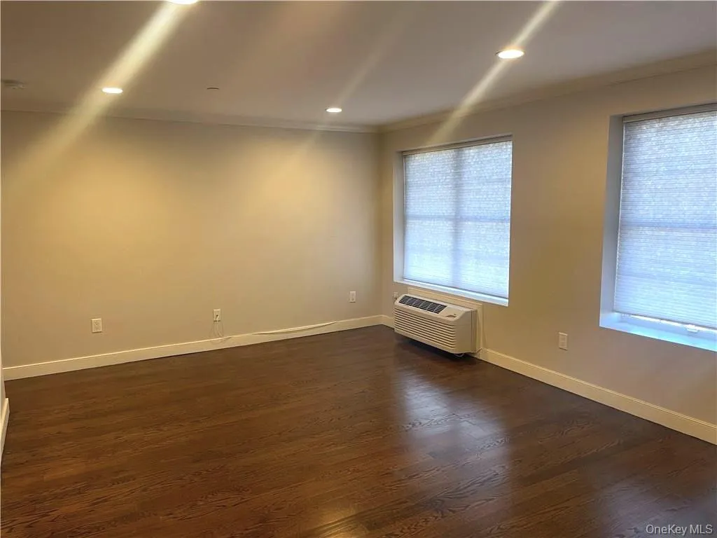 Unfurnished room featuring crown molding, dark wood-style flooring, recessed lighting, and a wall mounted air conditioner Unfurnished room featuring crown molding, dark wood-style flooring, recessed lighting, and a wall mounted air conditioner