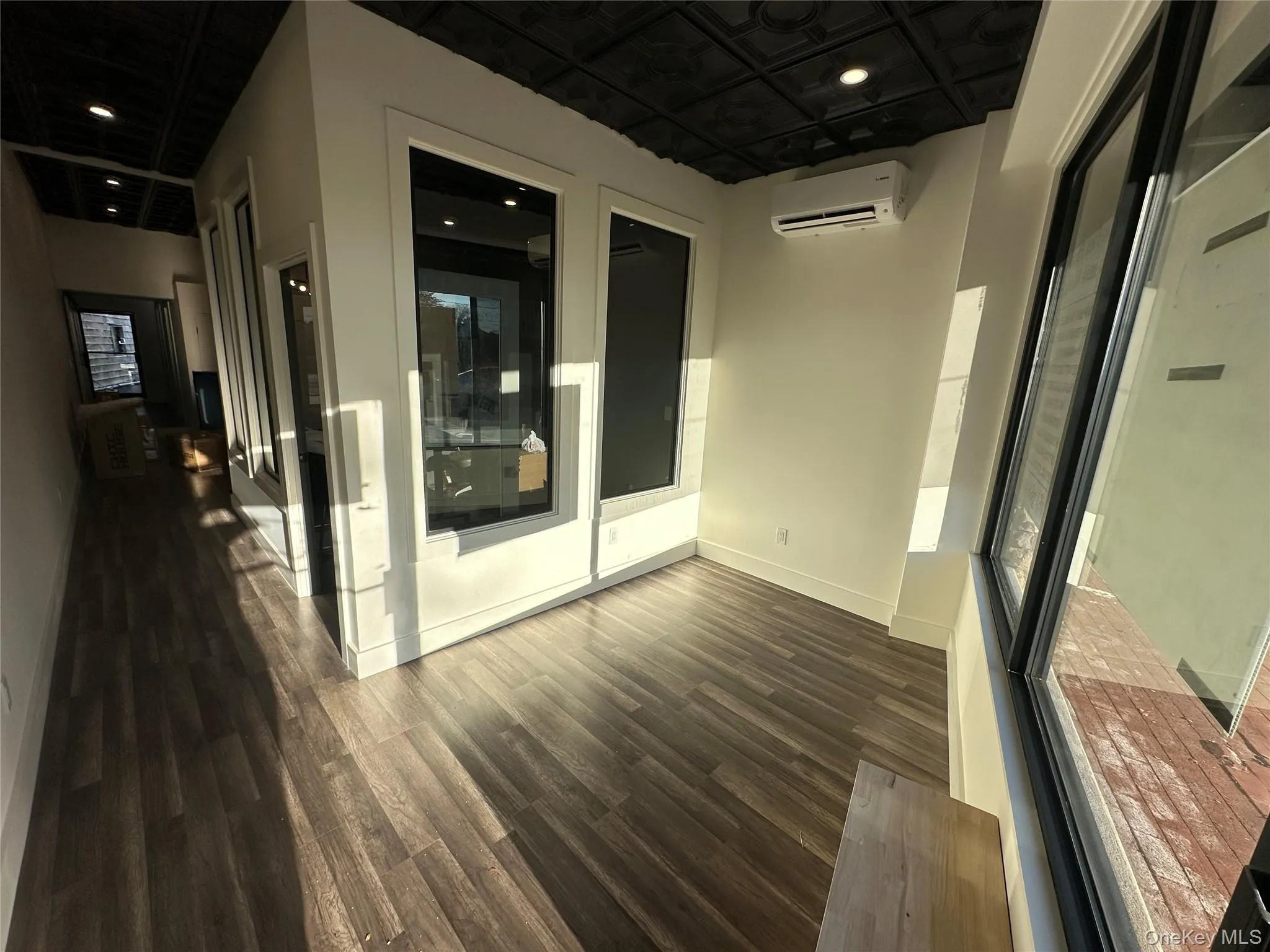 Unfurnished room with an ornate ceiling, dark wood-type flooring, a wall unit AC, and recessed lighting Unfurnished room with an ornate ceiling, dark wood-type flooring, a wall unit AC, and recessed lighting