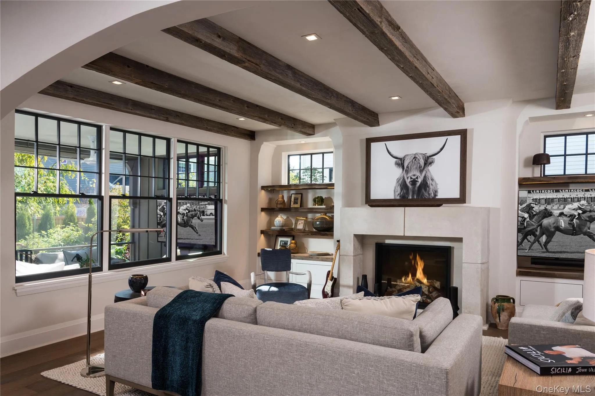 Living area with a warm lit fireplace, wood finished floors, beamed ceiling, recessed lighting, and built in features Living area with a warm lit fireplace, wood finished floors, beamed ceiling, recessed lighting, and built in features