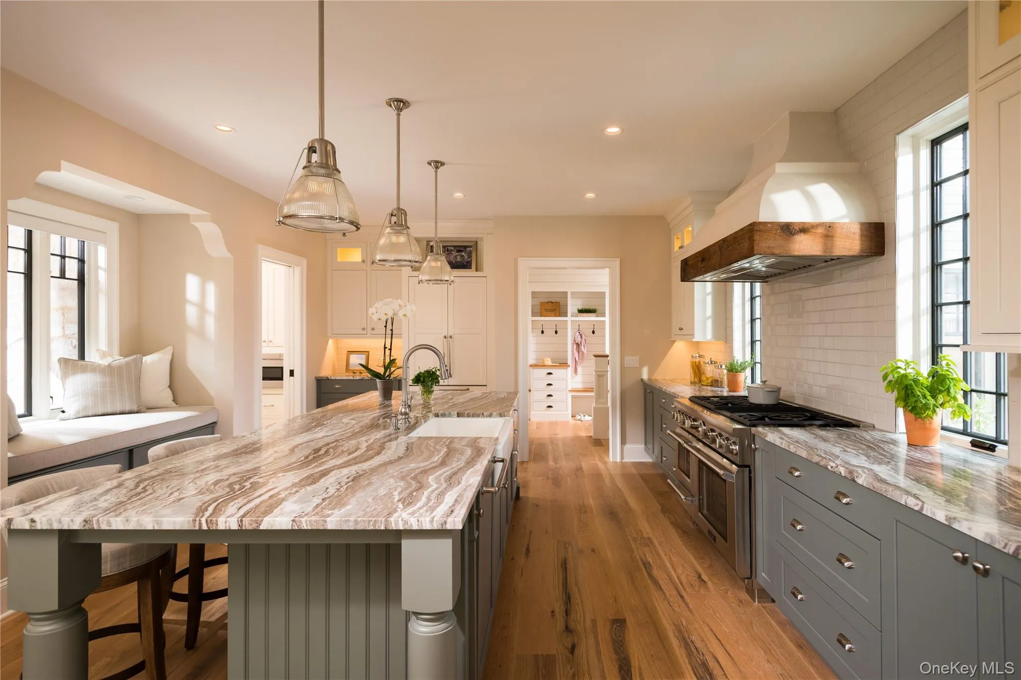 Kitchen with plenty of natural light, gray cabinets, custom exhaust hood, light stone countertops, and recessed lighting Kitchen with plenty of natural light, gray cabinets, custom exhaust hood, light stone countertops, and recessed lighting