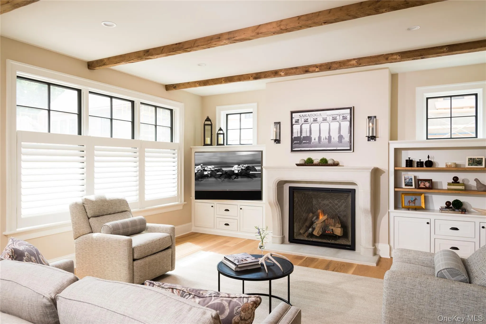 Living area featuring a lit fireplace, light wood-type flooring, beam ceiling, and recessed lighting Living area featuring a lit fireplace, light wood-type flooring, beam ceiling, and recessed lighting
