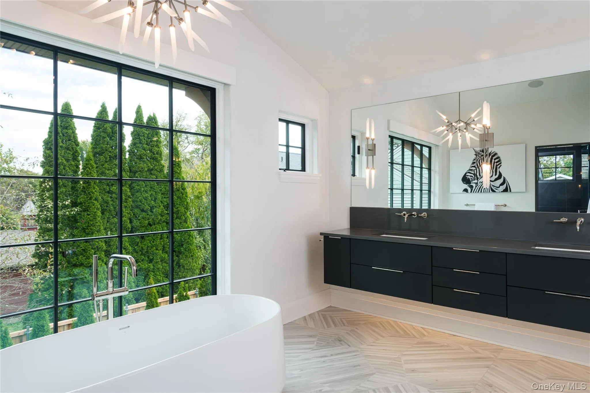 Full bathroom with a chandelier, double vanity, a freestanding bath, vaulted ceiling, and healthy amount of natural light Full bathroom with a chandelier, double vanity, a freestanding bath, vaulted ceiling, and healthy amount of natural light